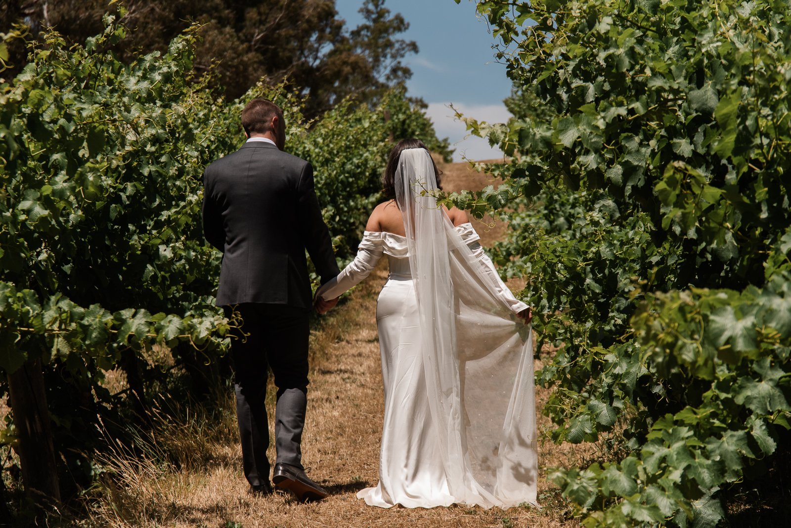 Newlyweds walking through the vines at a Rutherglen vineyard wedding