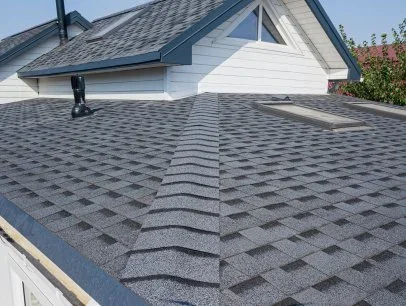 Close-up of a gray shingled roof of a house with a dormer window and a vent tube.