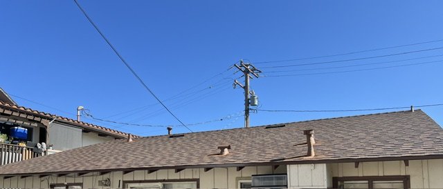 View of the roof and power lines against a clear blue sky.