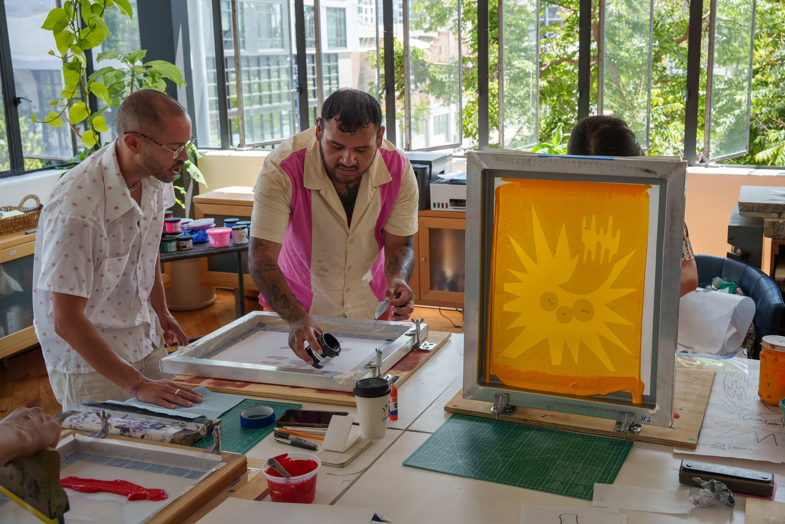 Two people work on screen printing at the print studio.