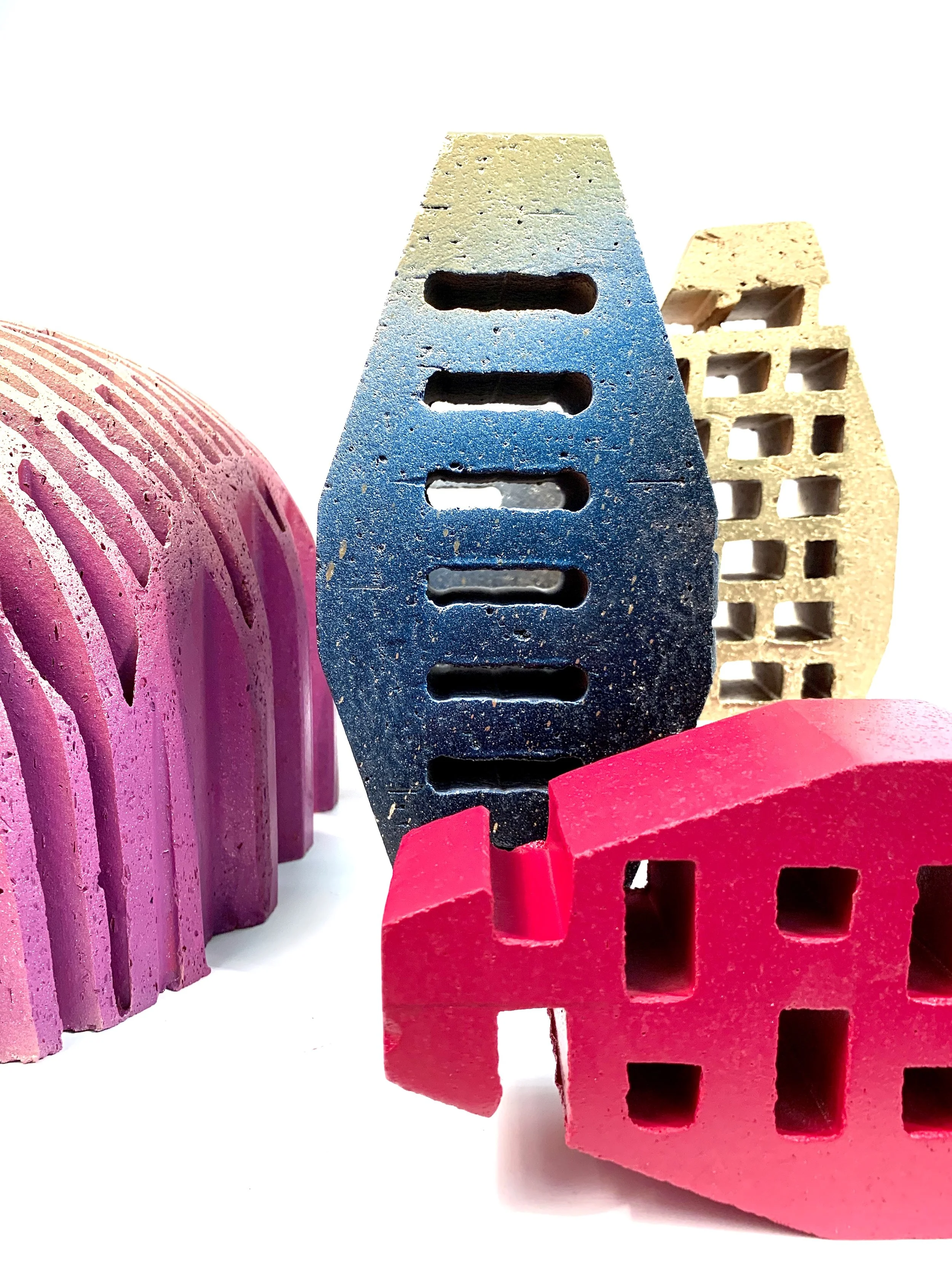 Close-up of colorful erasers in pink, blue, and yellow, arranged in a row against a white background.
