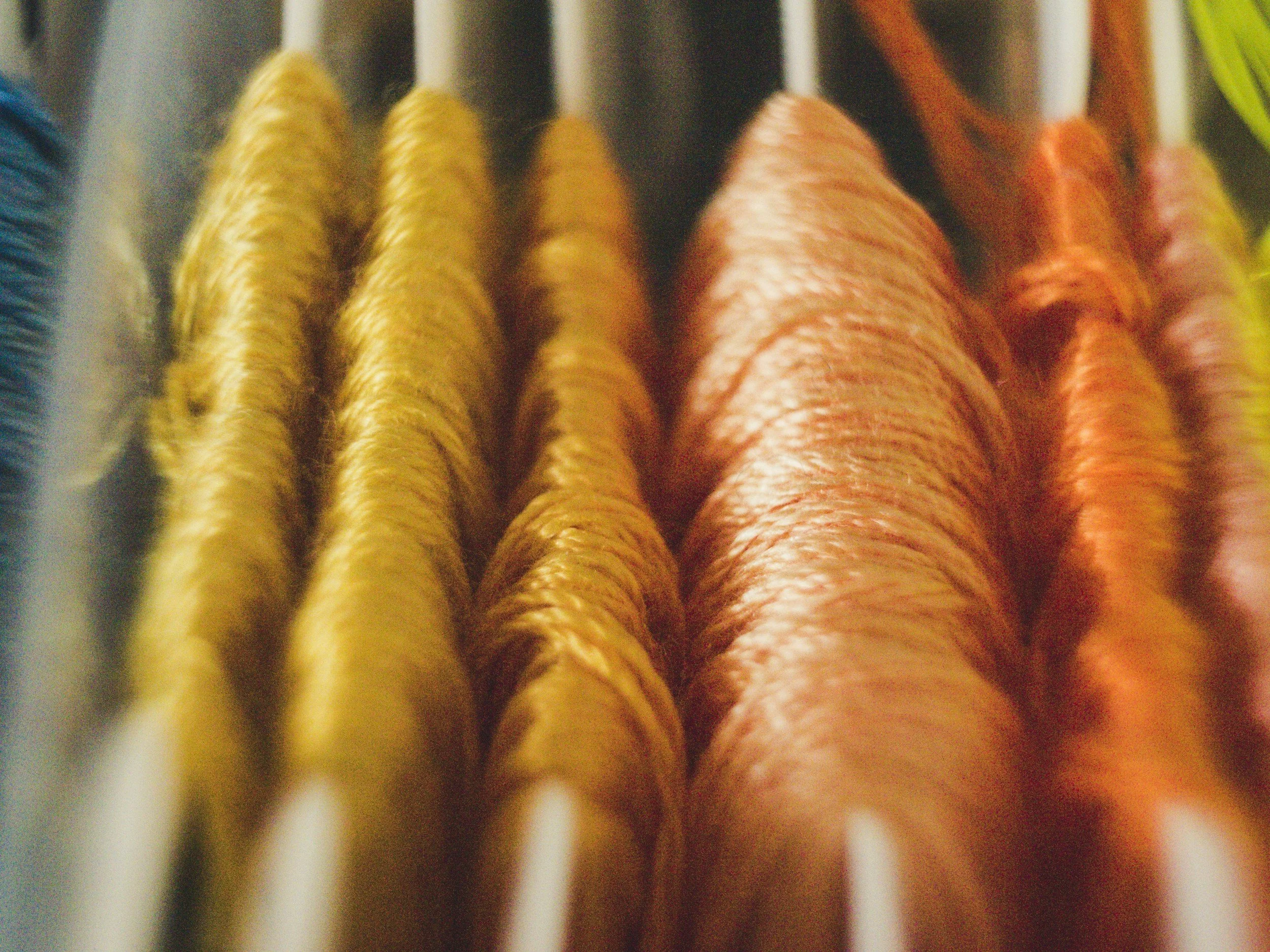 Close-up of embroidered colored thread embroidery on fabric, showing yellow, pink, orange, and green thread.