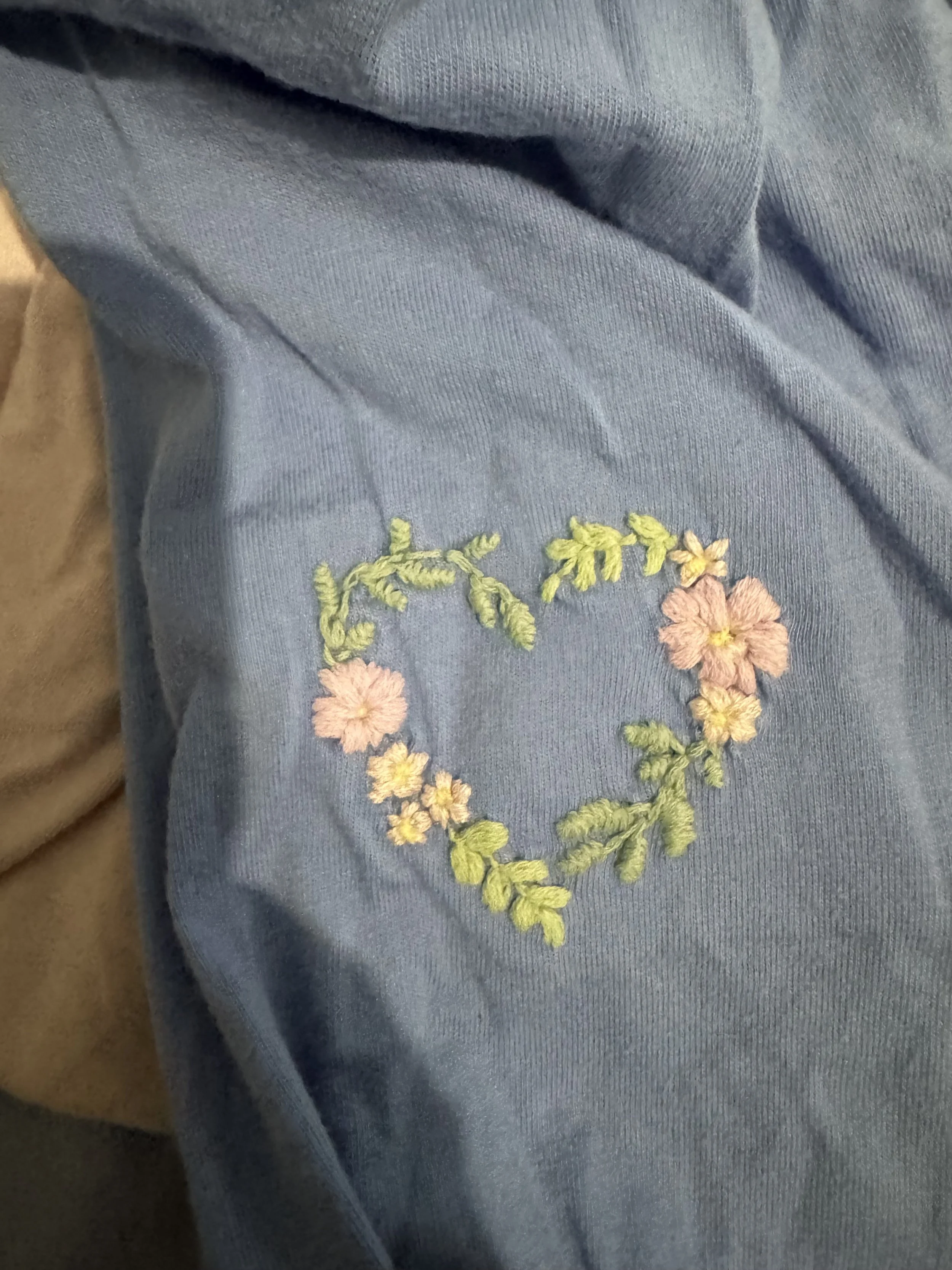 Close-up of blue fabric clothing with embroidered floral design.