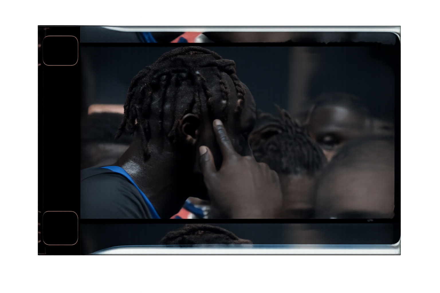 A person with dreadlocks is inside a microwave oven looking at their reflection on the oven door, with a hand touching their ear.