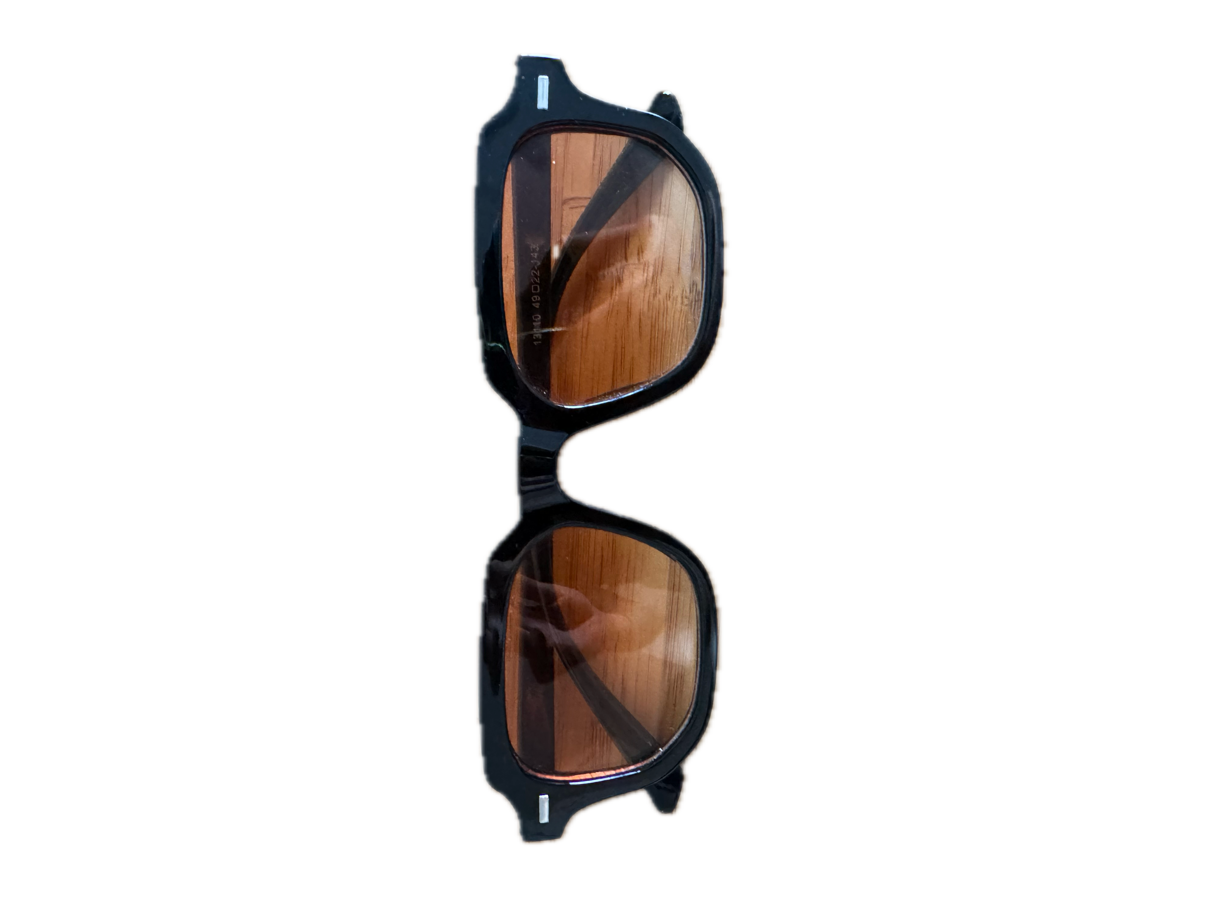 Pair of sunglasses with dark frames and tinted lenses placed on a reflective surface.