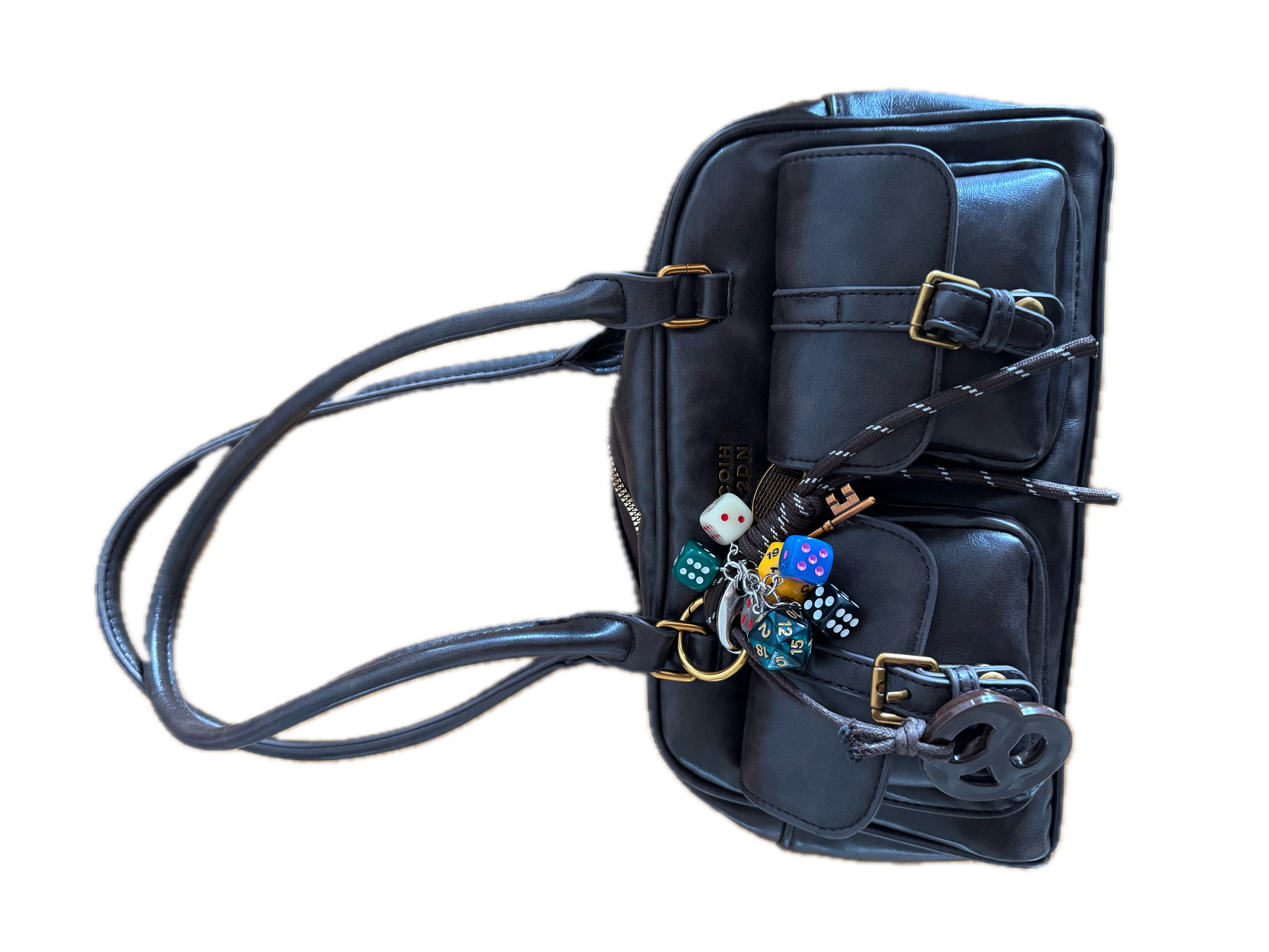A black leather backpack with gold accents and multiple compartments, surrounded by various gaming dice and a pair of earbuds.