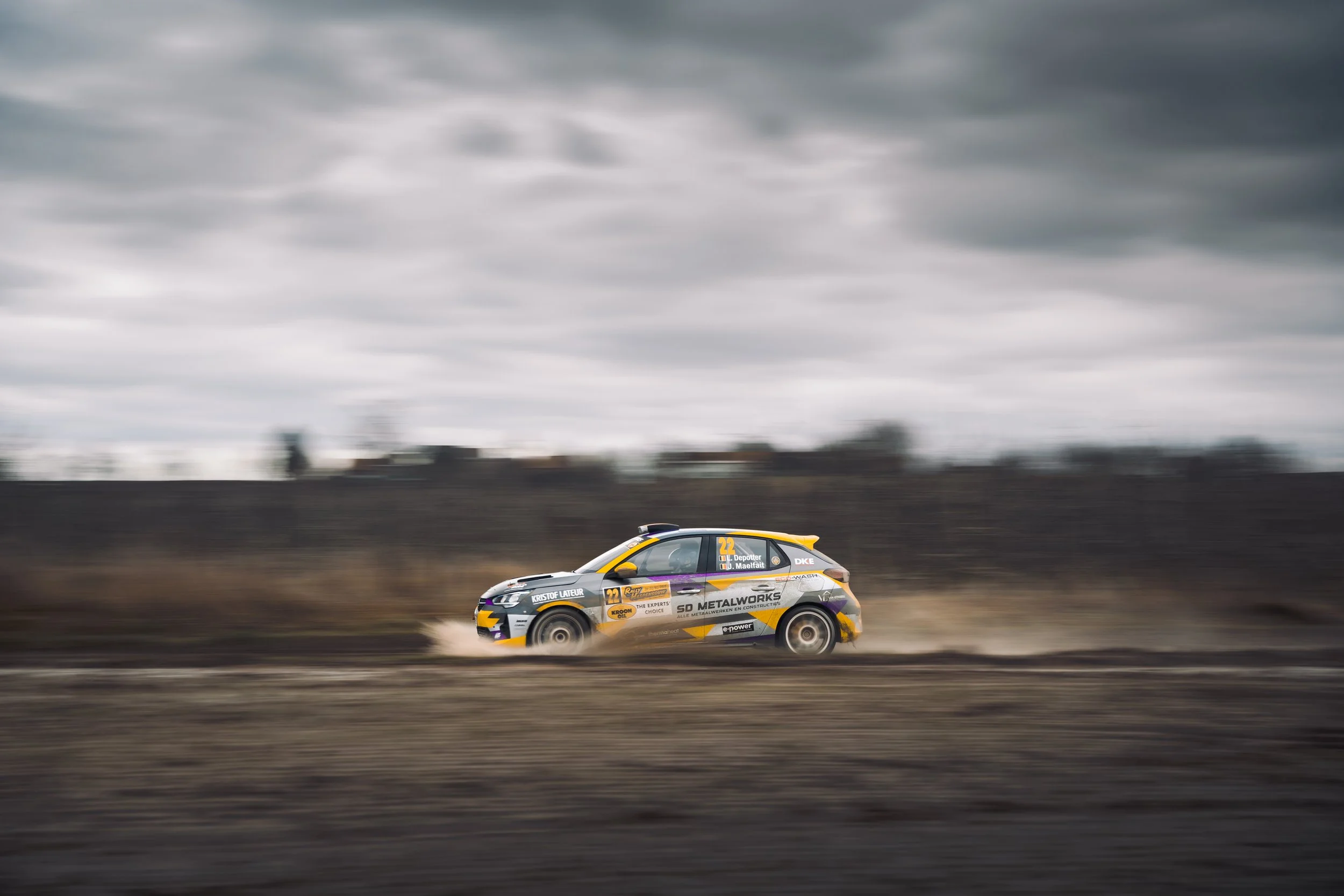 A race car speeding down a track under a cloudy sky.