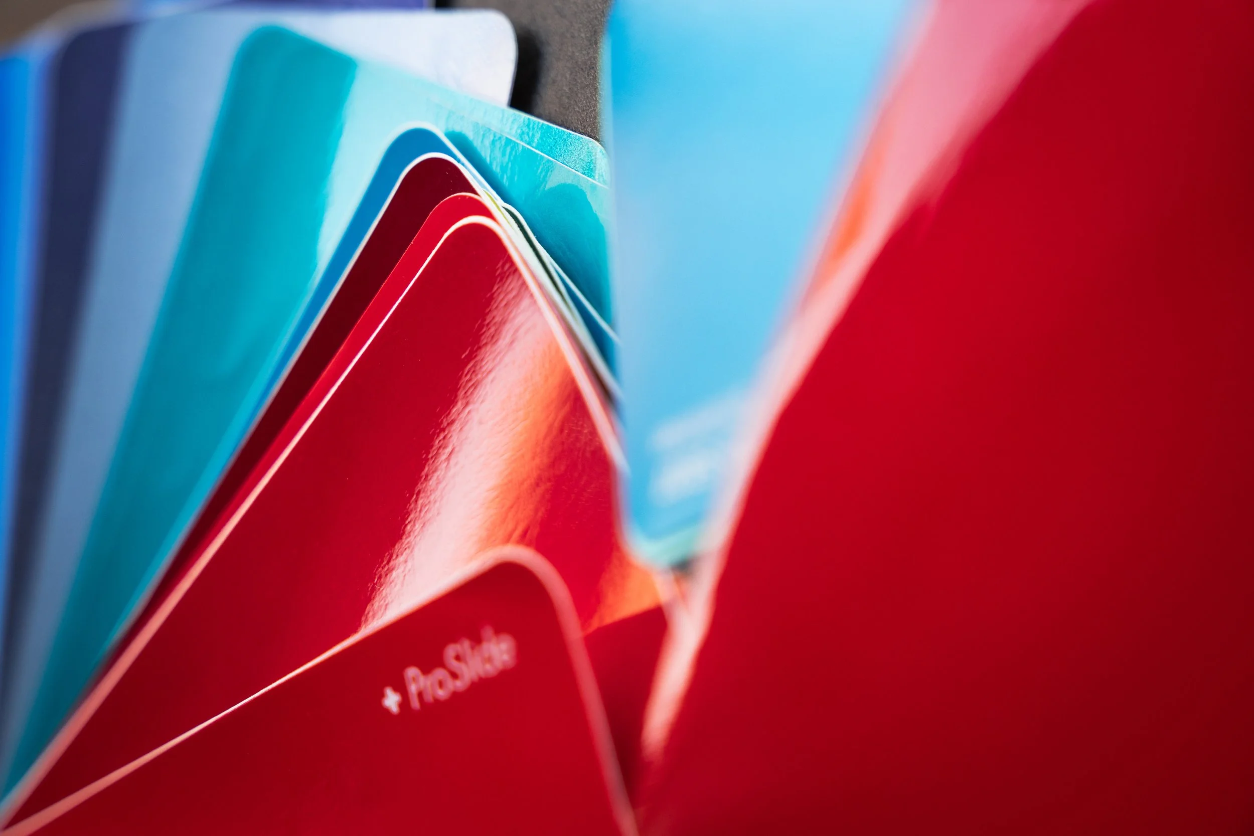 Close-up of colorful cards or tabs, with shades of blue, red, and orange, arranged in a fanned-out manner, possibly product or informational cards.