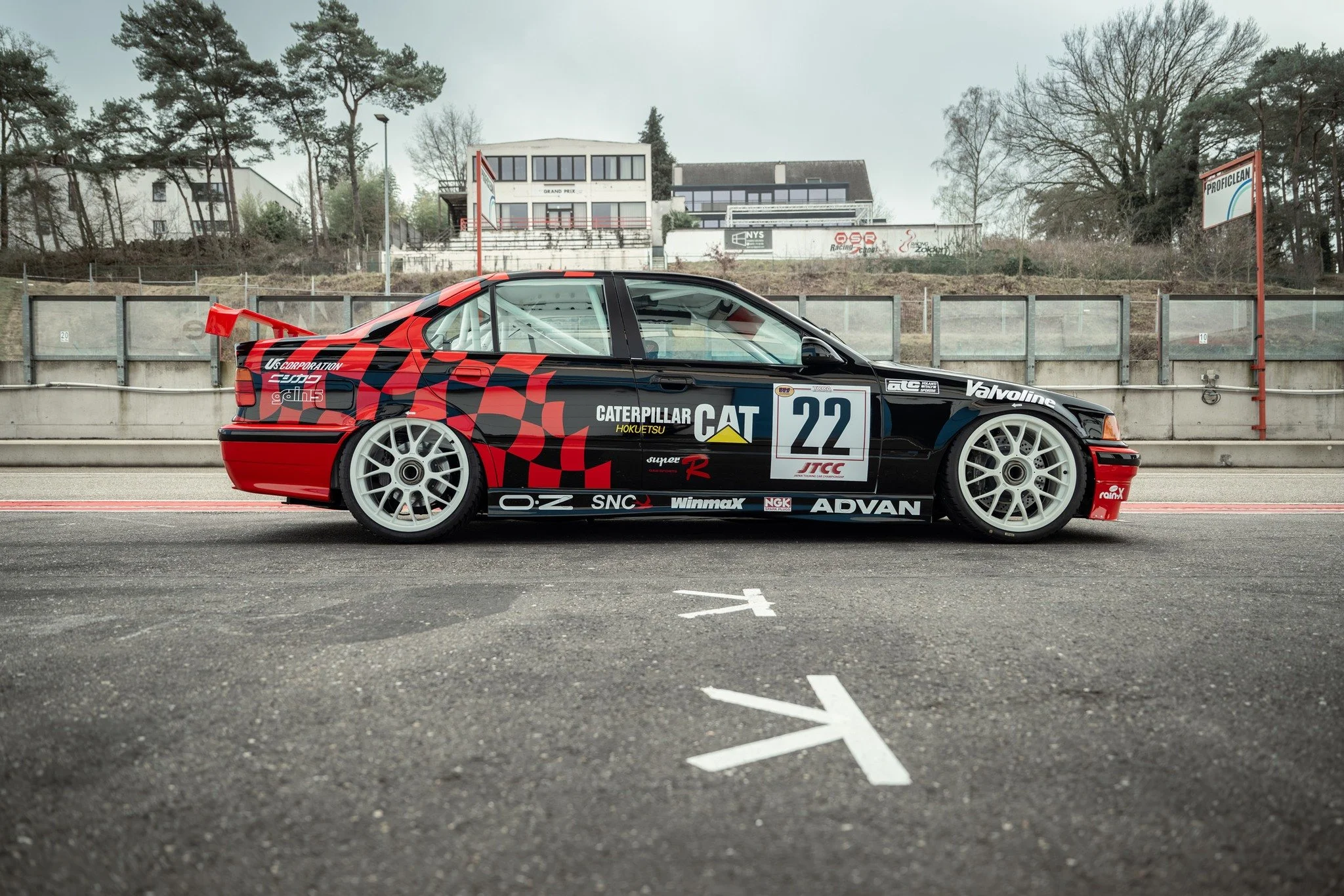 Race car on a racing track with empty grandstand in the background.