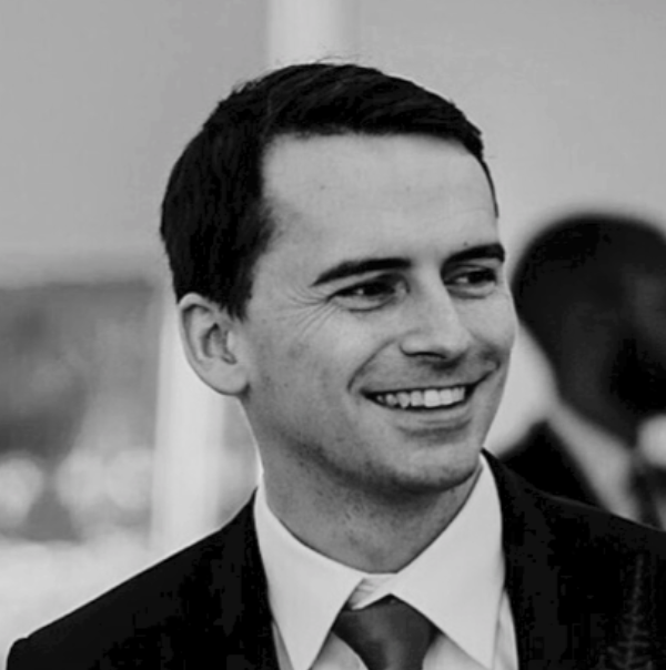 Black and white photo of a smiling young man in a suit and tie.