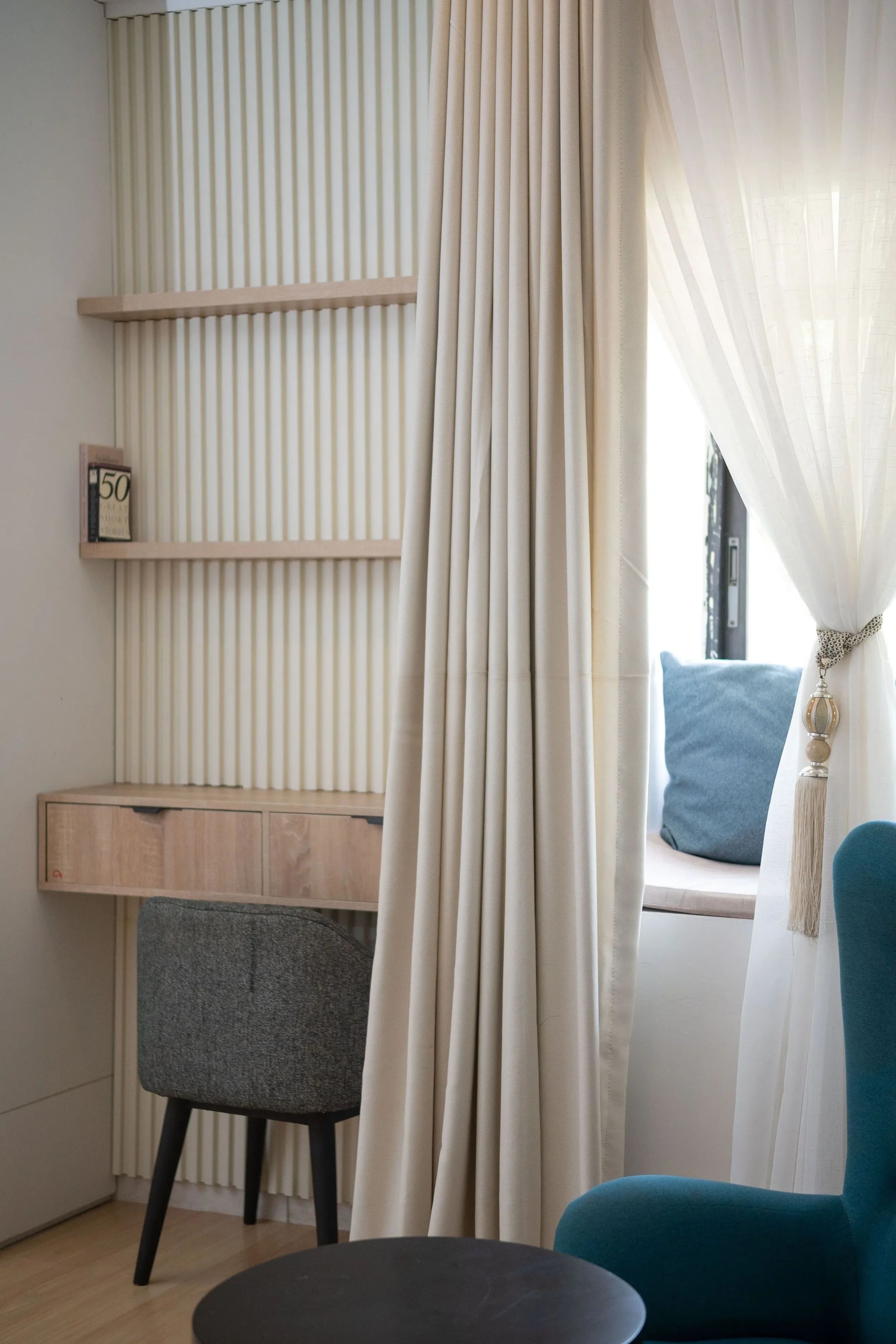Un coin bureau avec étagères en bois, un espace aux teintes claires et douces avec des jeux de matières textiles.