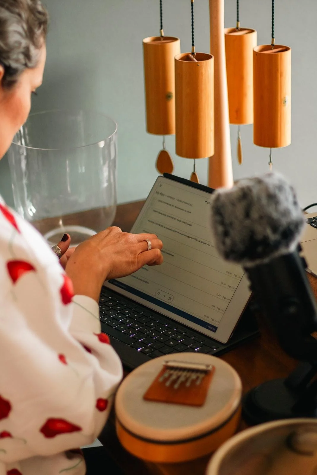 Une femme utilise une tablette à clavier, avec un micro posé devant elle, dans un environnement intérieur contemporain.