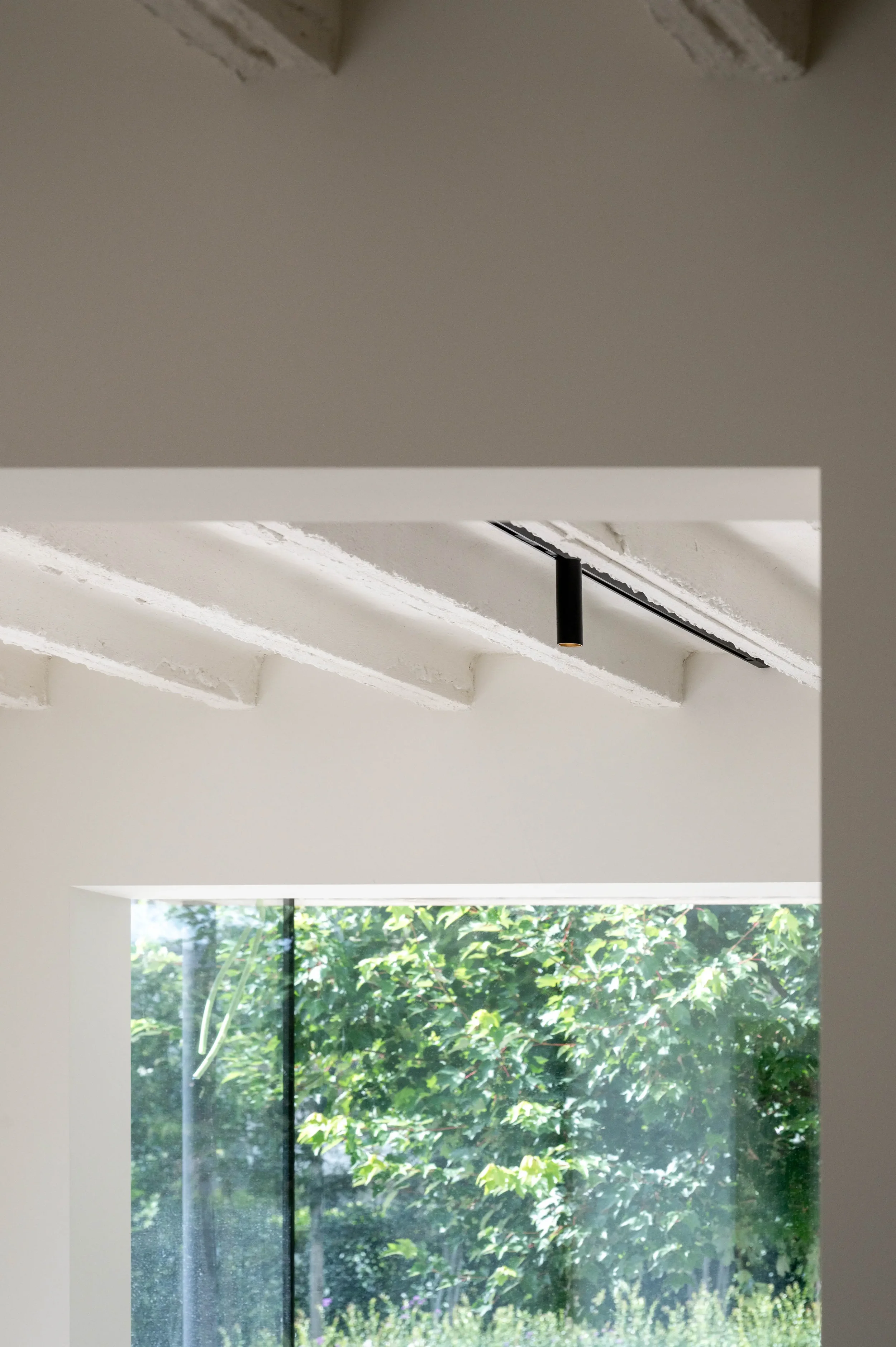uitbreiding woning - interieur met behoud van vrijgekomen betonnen plafond - afwerking in kalei - verlichting via spots op rail