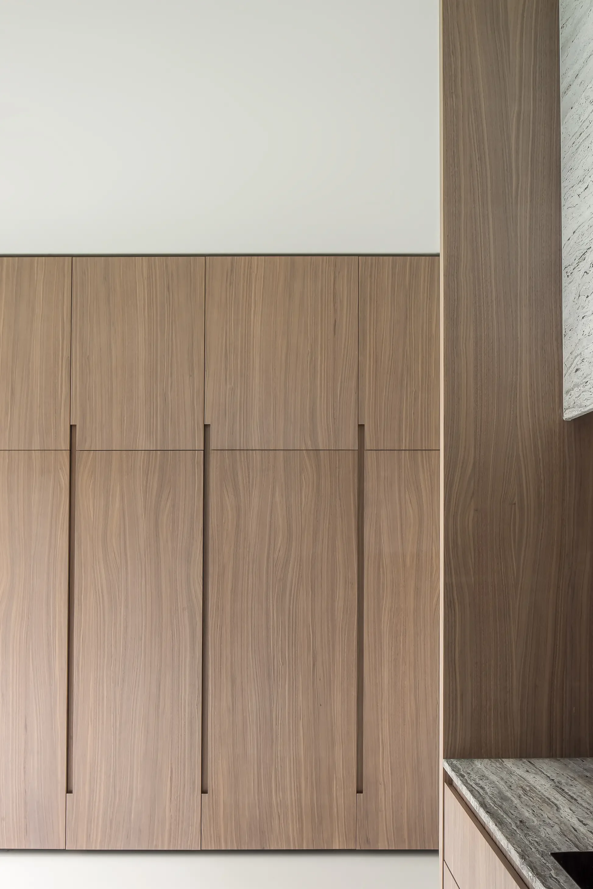 Close-up view of a modern kitchen with light wood cabinets and a natural stone countertop.