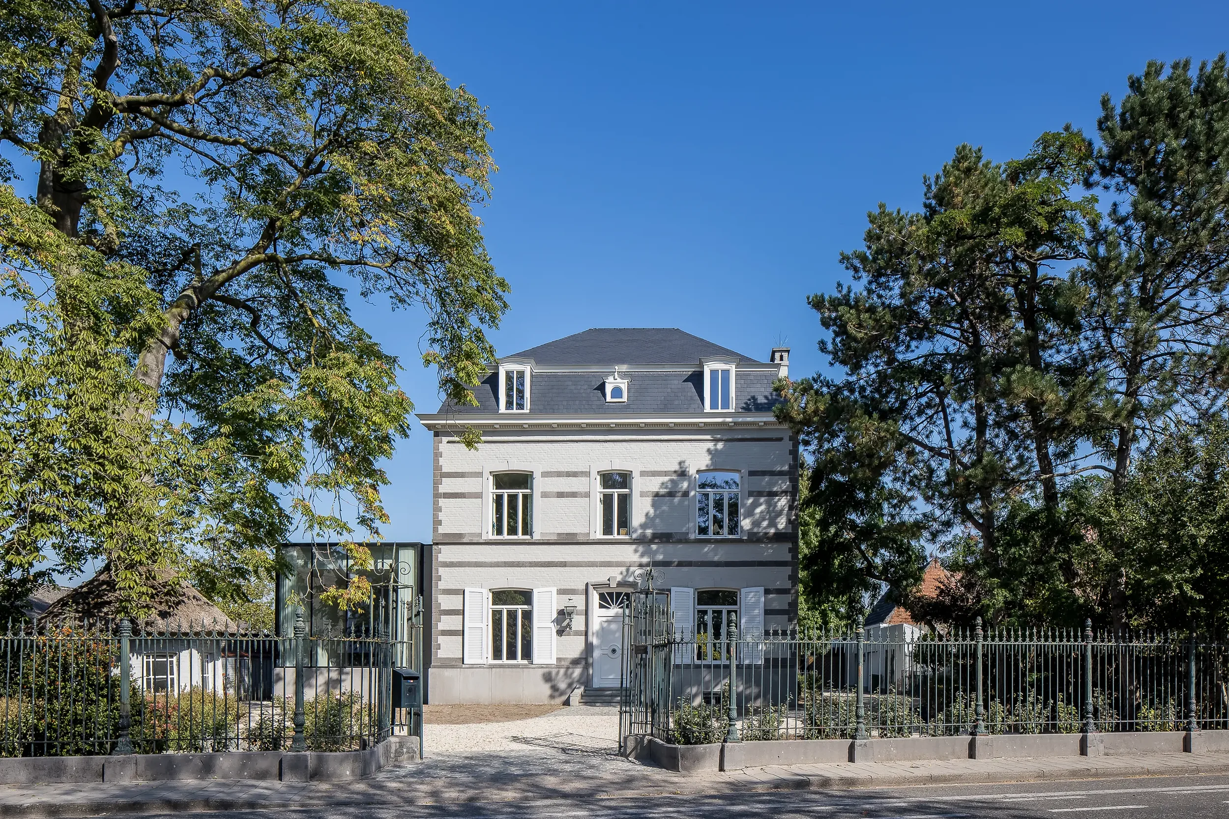 A modern extension of a classic house with a clear blue sky in the background.