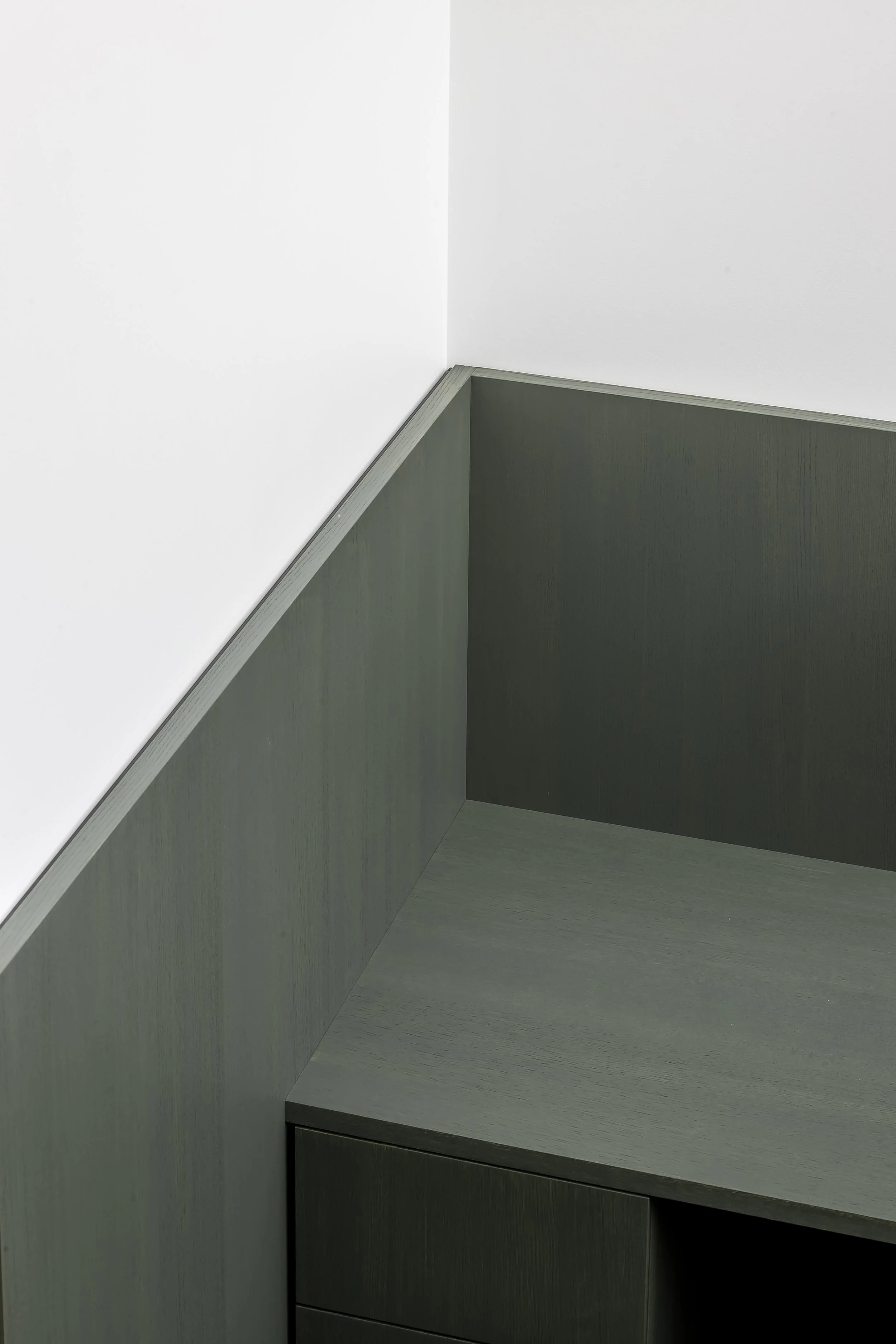 Corner of a room with a white wall, a gray wood cabinet, and a matching countertop.