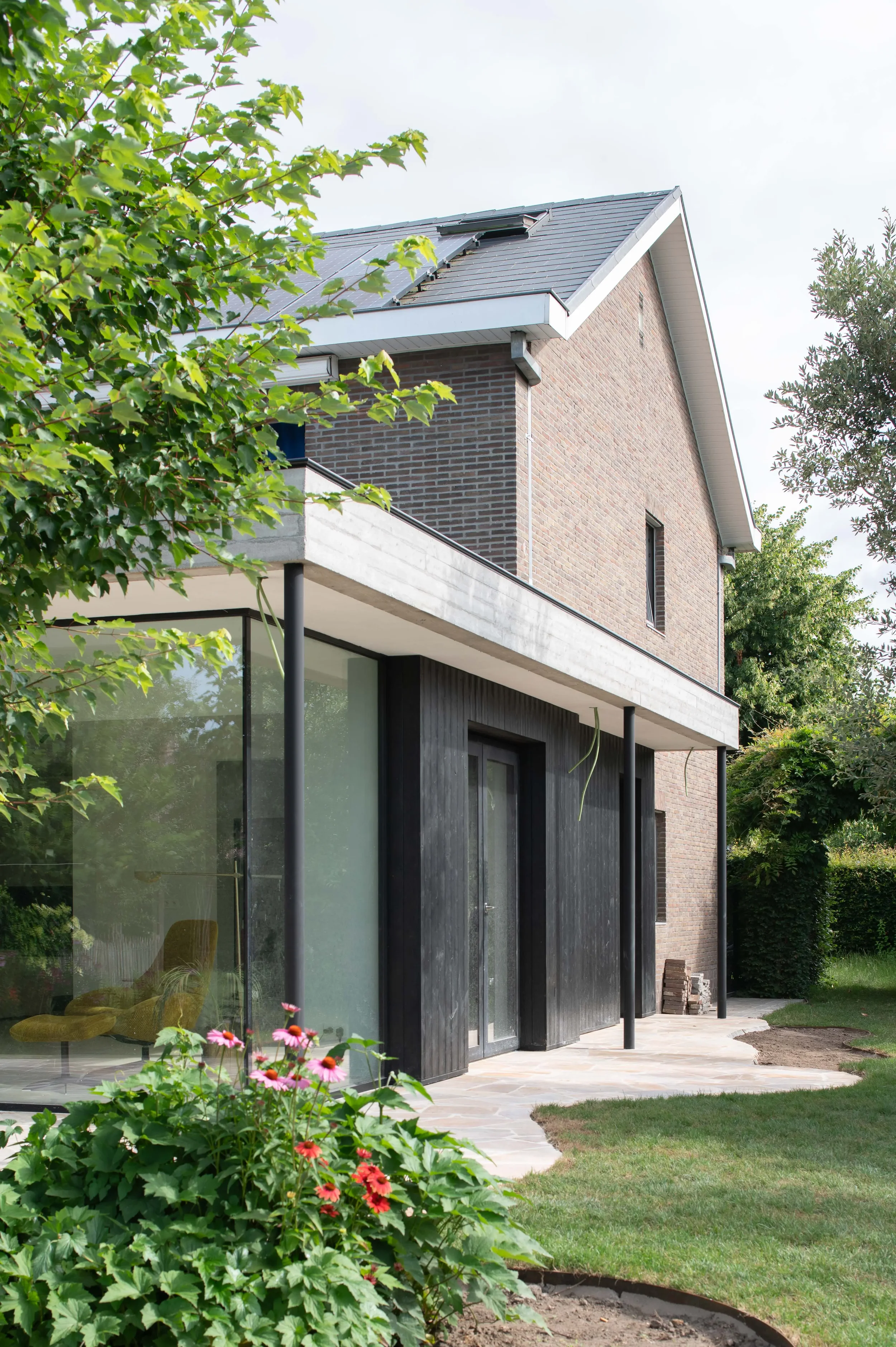 uitbreiding halfopen woning met luifel in zichtbeton en gevels in zwarte houten gevelbekleding