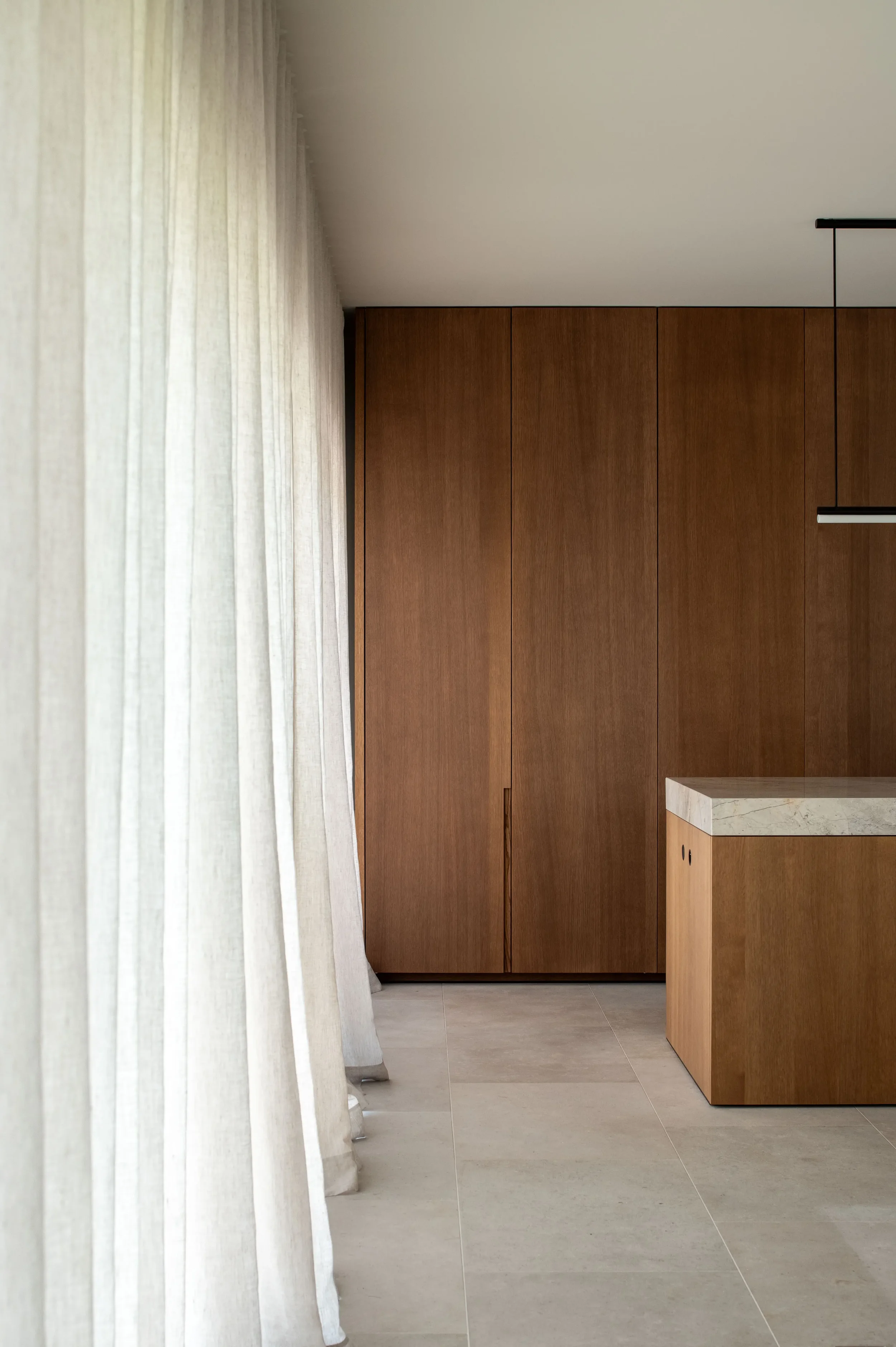 interieur beeld van sobere keuken in notelaarfineer en linnen gordijenen