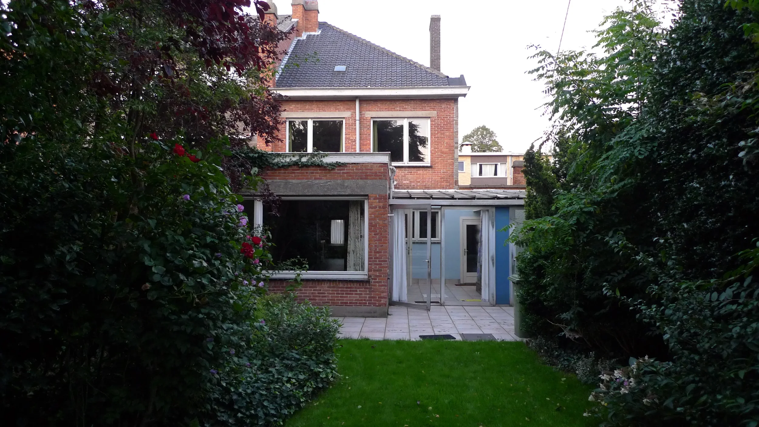 Oude achtergevel van de rijwoning uit 1964 met veranda, gezien vanuit de tuin