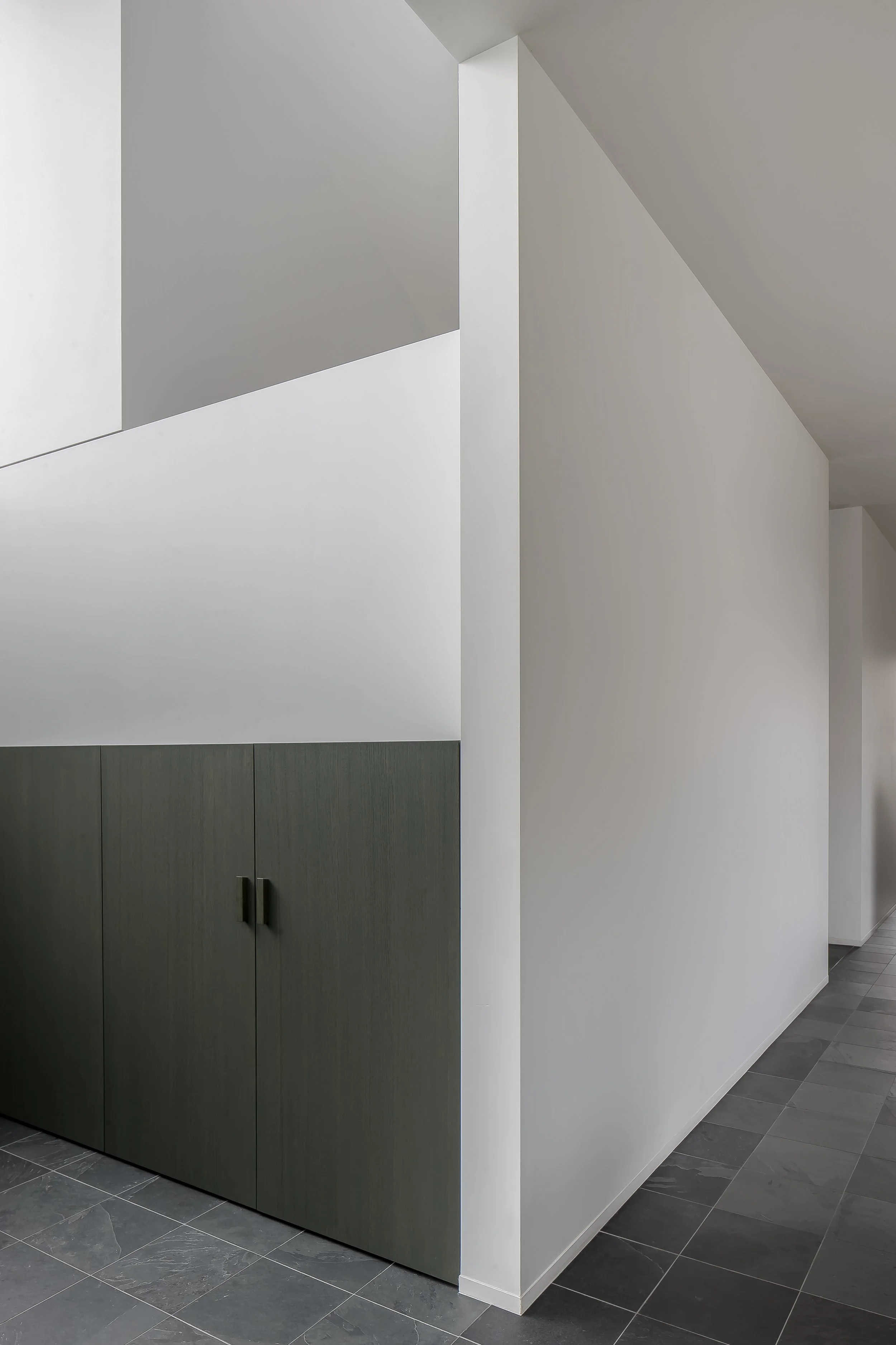 Modern interior with white walls, gray cabinets, taupe and gray tiled flooring, and a structural column.