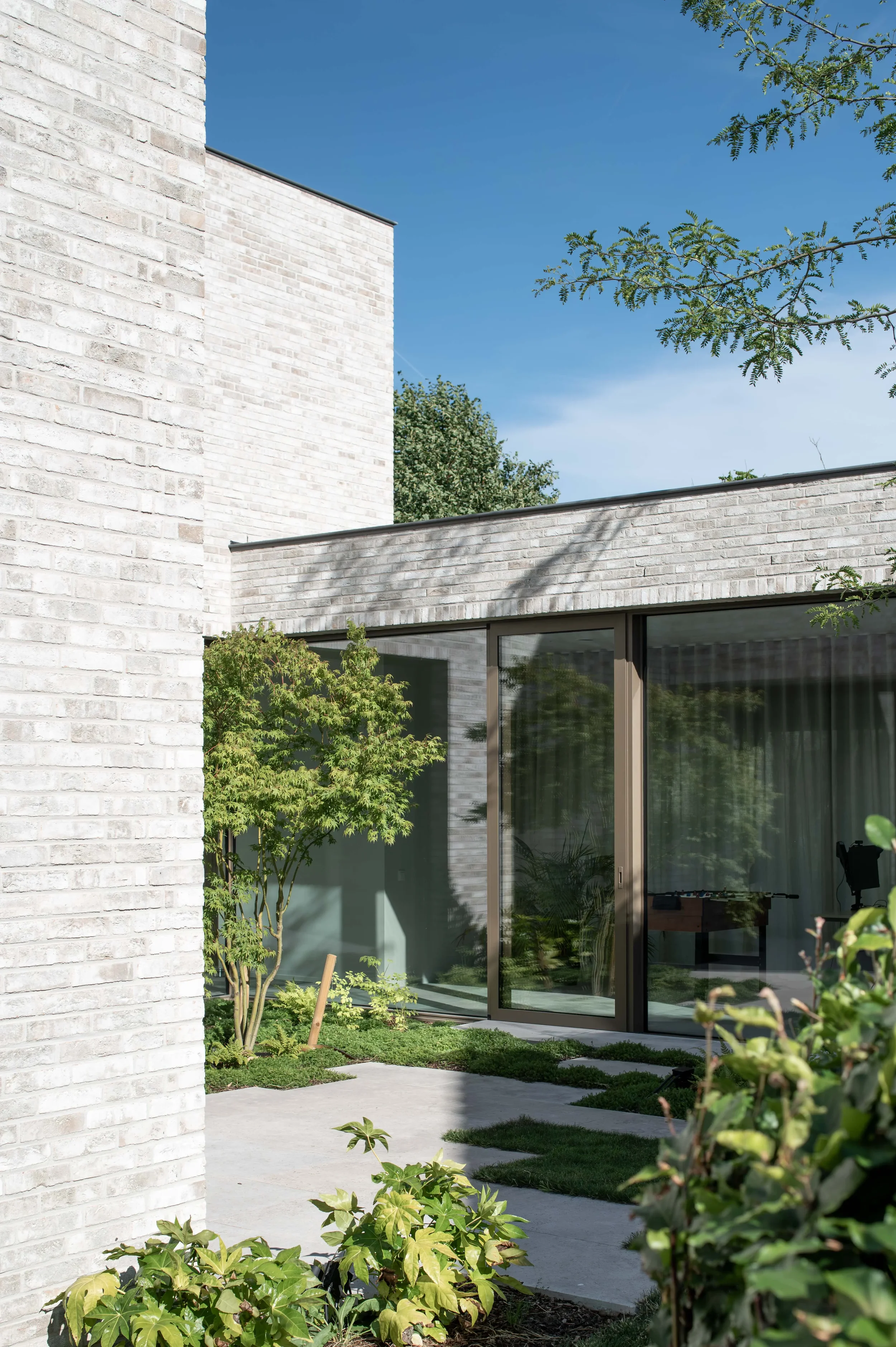 binnenpatio van een eengezinswoning met handvormsteen en bronskleurig aluminium schrijnwerk