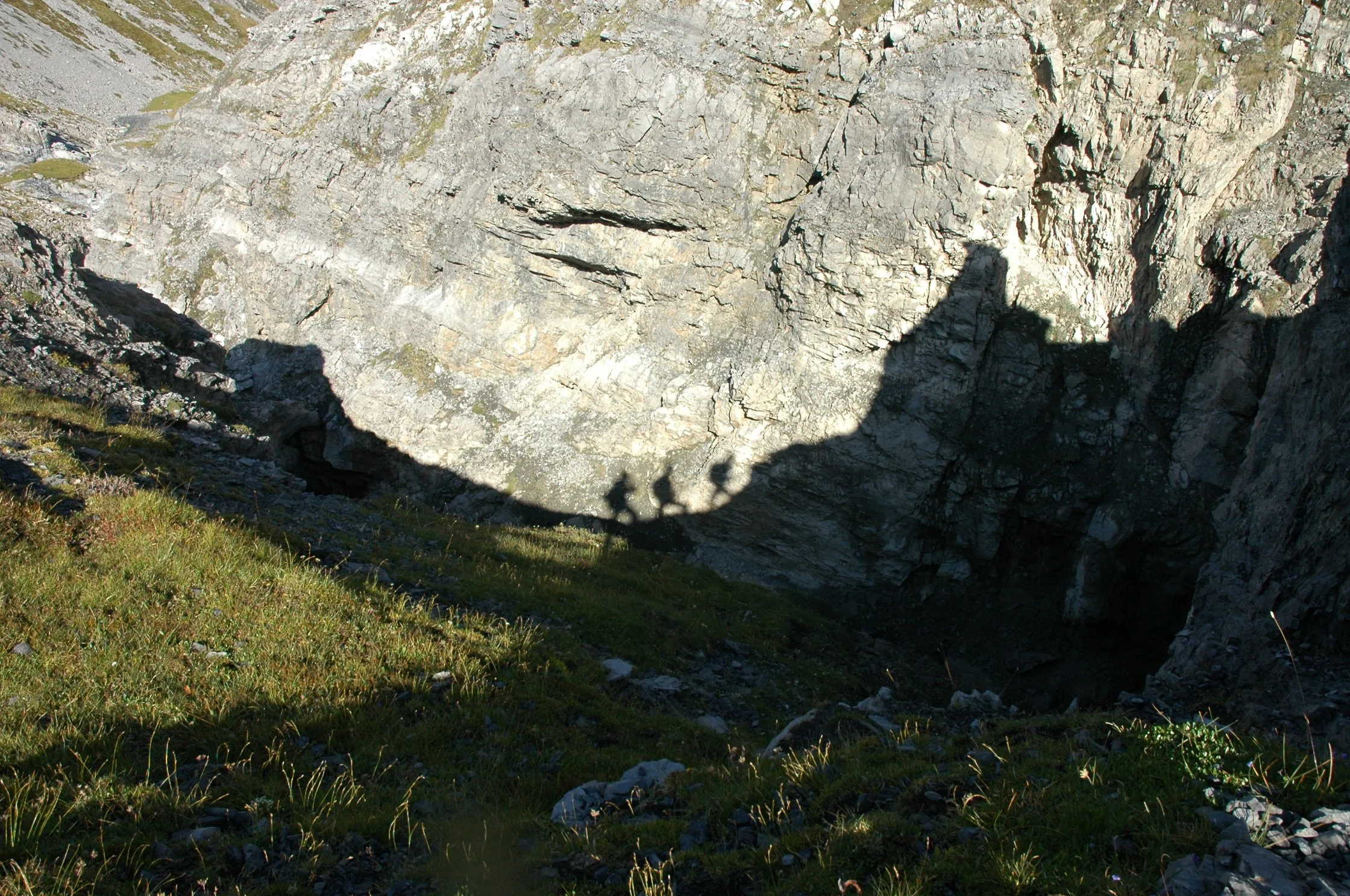 Parete rocciosa e valle con vegetazione in primo piano.