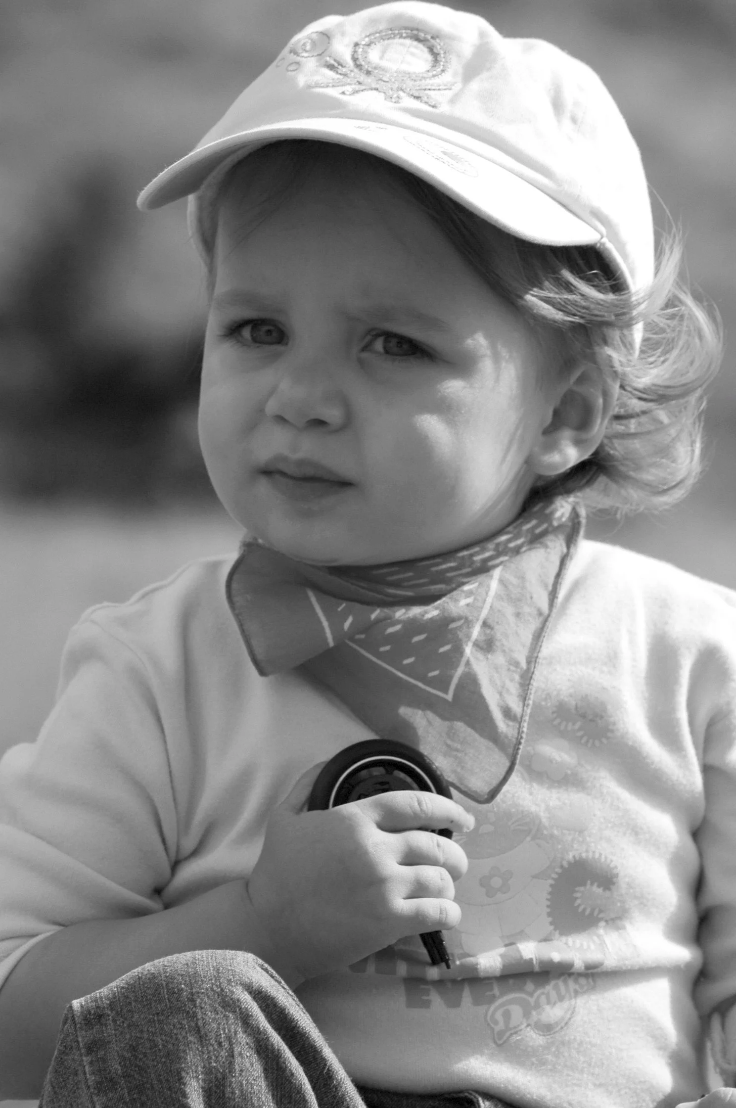 Ragazza giovane con cappellino e felpa, che tiene un microfono, vista frontale, fotografie in bianco e nero.