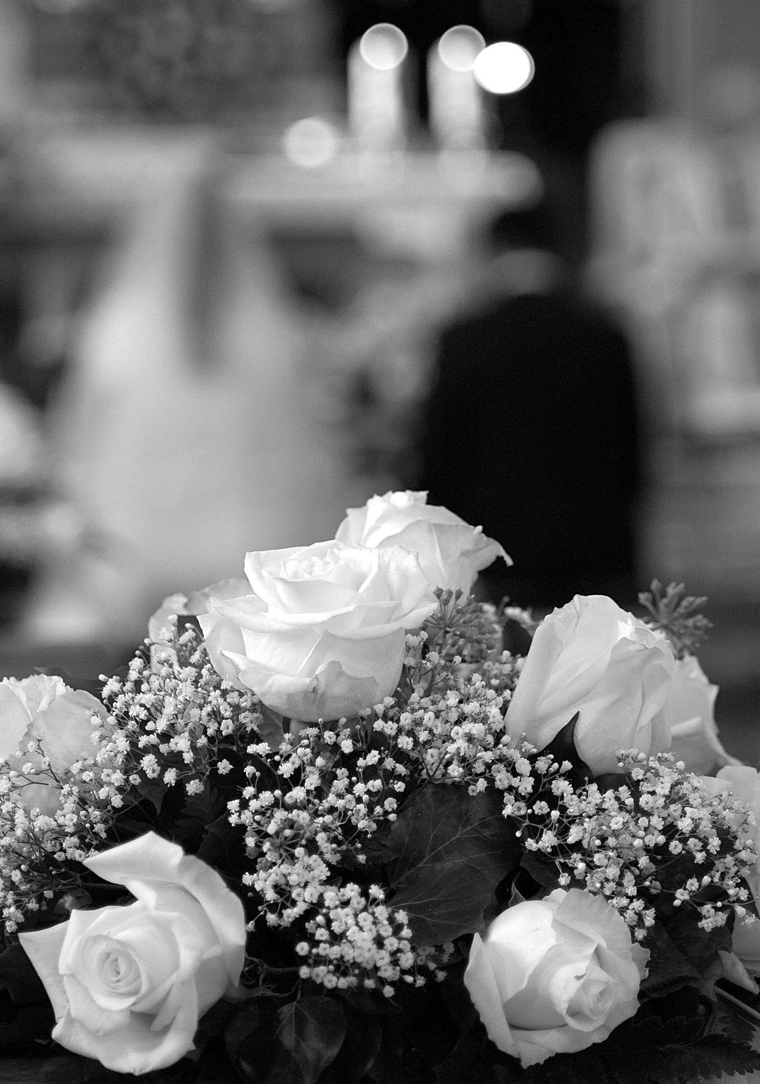 Un mazzo di fiori con rose bianche e fiori di baby breath, sfondo sfocato con luci