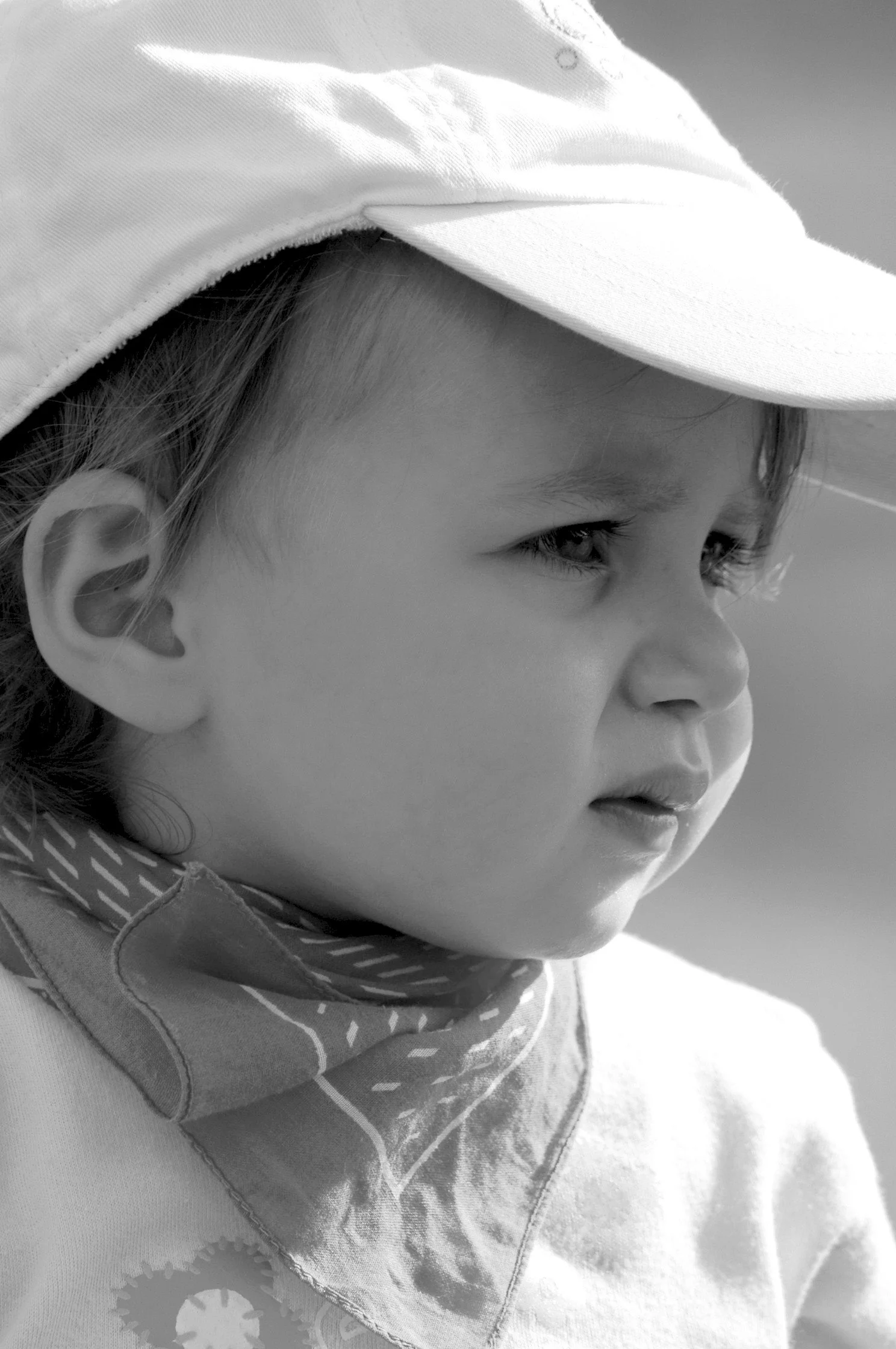 Ragazzo giovane con cappello bianco, giacca e sciarpa, in primo piano, ritratto in bianco e nero.