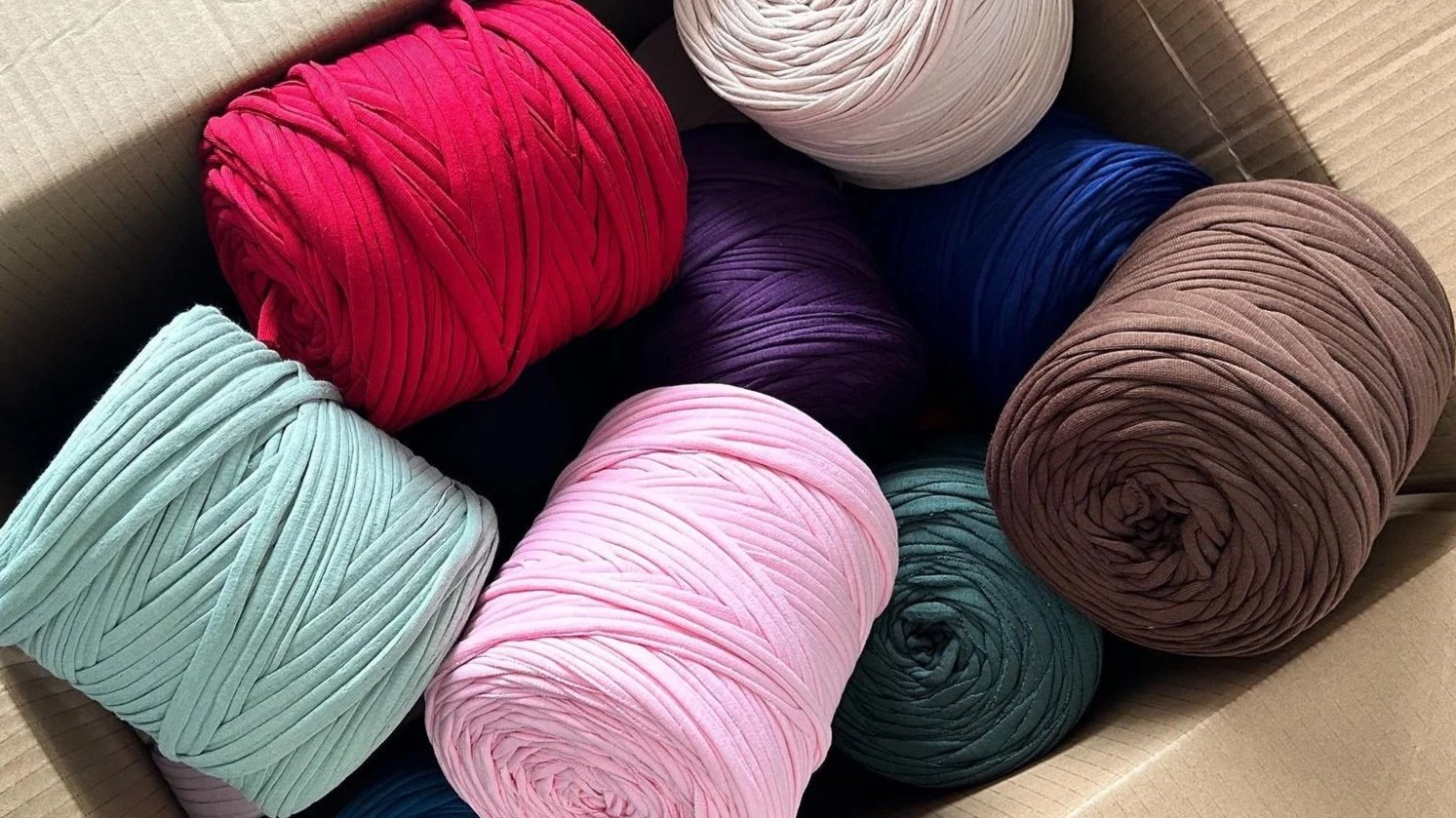 Nastro di tessuto di vari colori arrotolato in una scatola di cartone