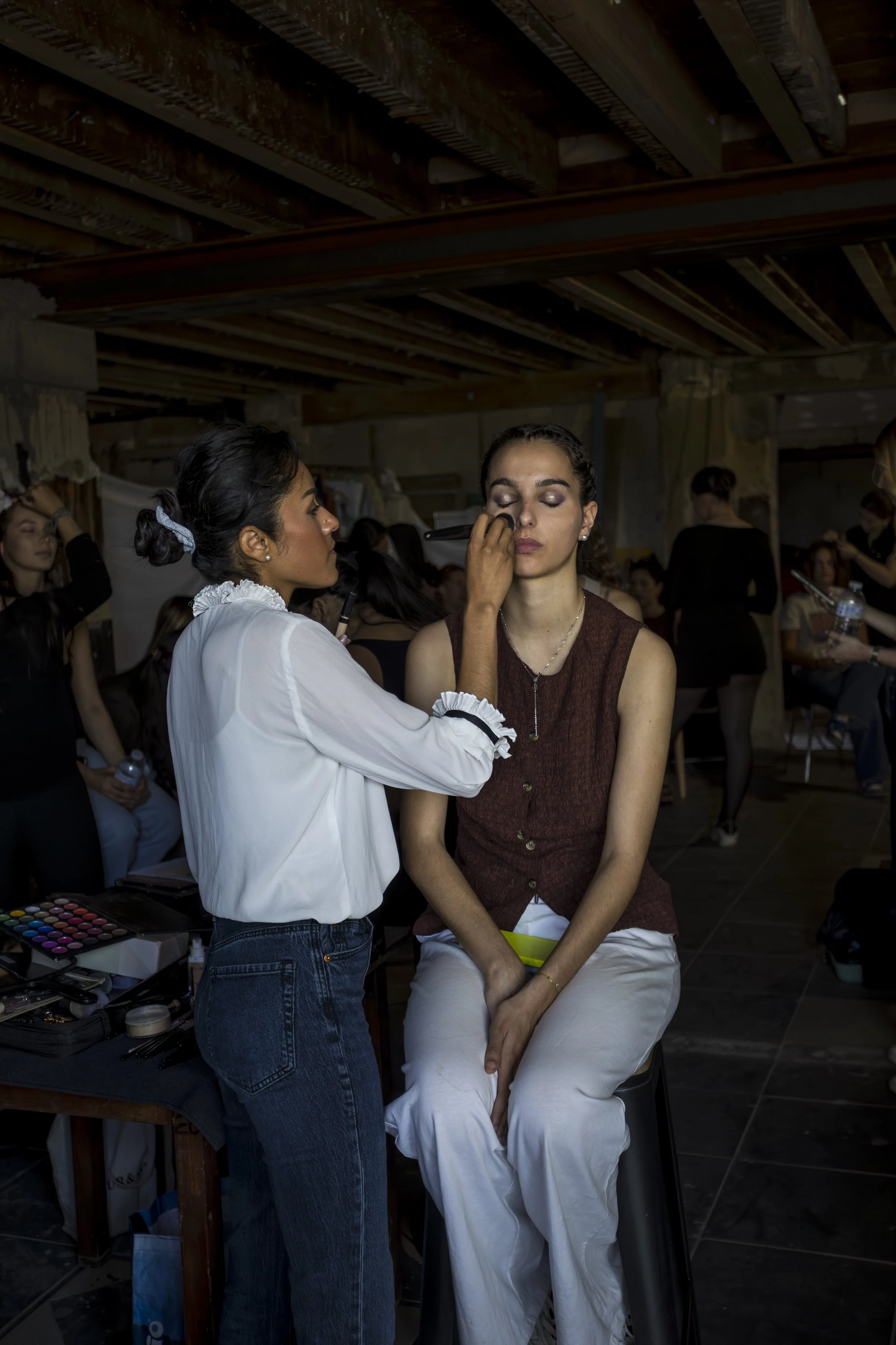 Une équipe de maquilleurs prépare une femme pour un tournage ou un événement, maquillage en cours, plusieurs personnes en arrière-plan