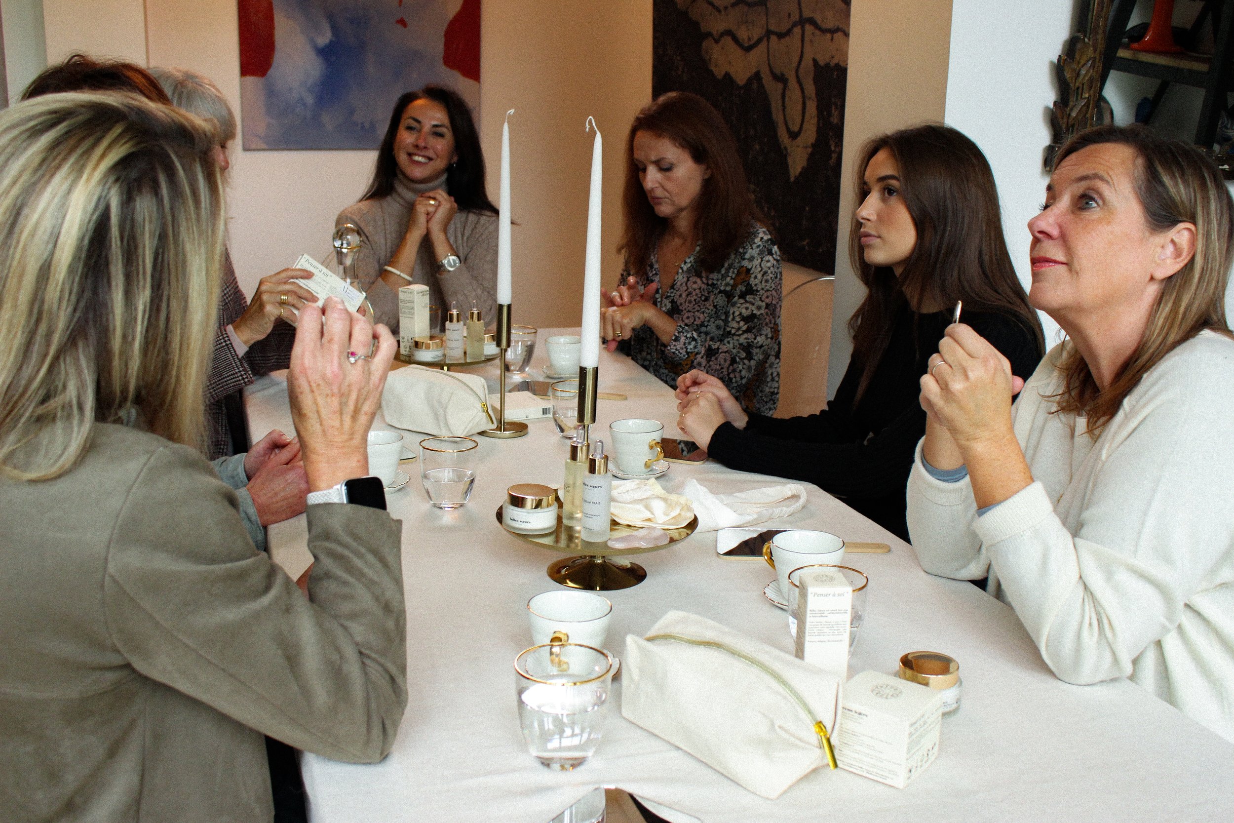 Groupe de femmes assises autour d'une table, discutant et souriant, dans un cadre intérieur.