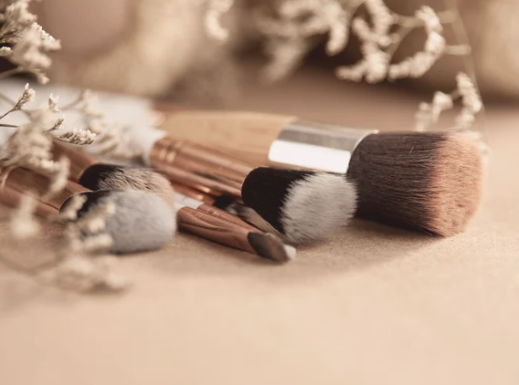 pinceaux de maquillage sur une surface, entourés de fleurs séchées