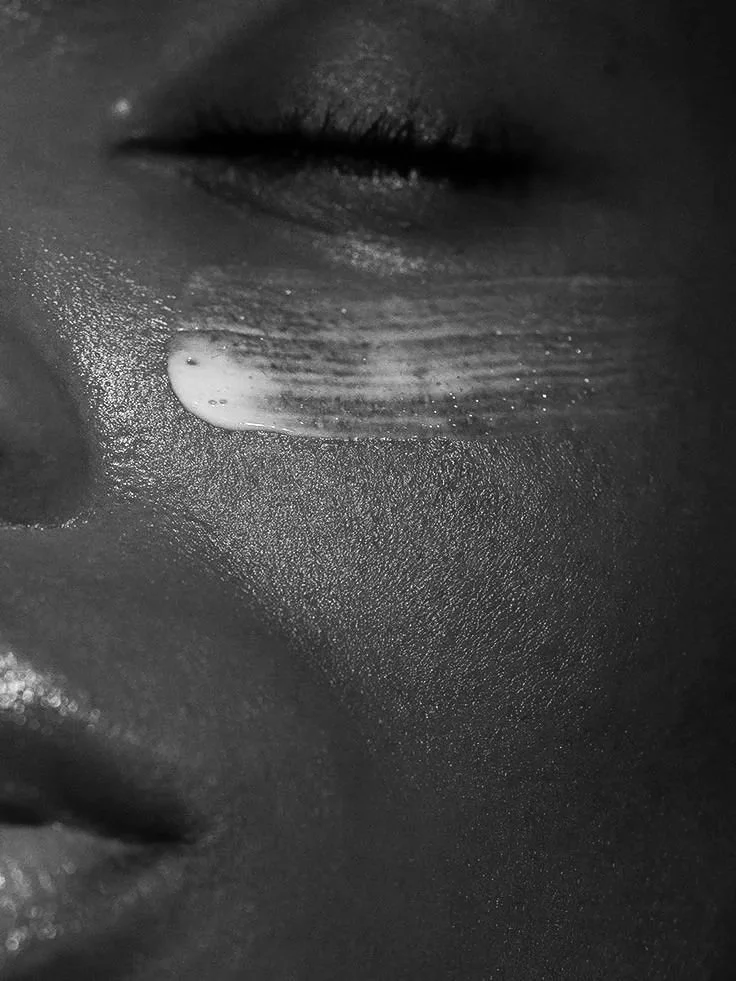 Gros plan d'un visage féminin en noir et blanc, avec une larme sur la joue et un œil fermé.
