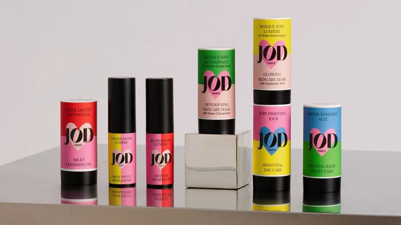 Une collection de plusieurs pots de produits cosmétiques de la marque JOD Paris, comprenant des huiles, des mascaras, des baumes et des crèmes, alignés sur une surface blanche.