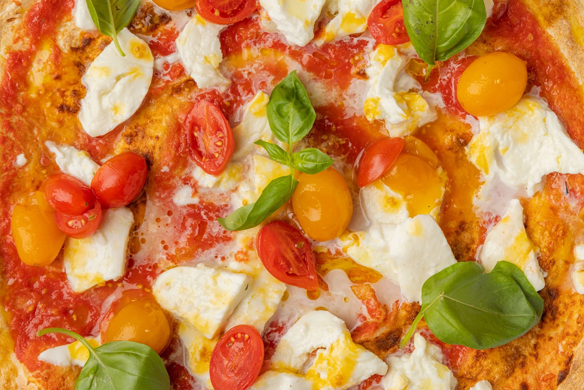 Pizza con pomodorini, mozzarella, basilico e uova.