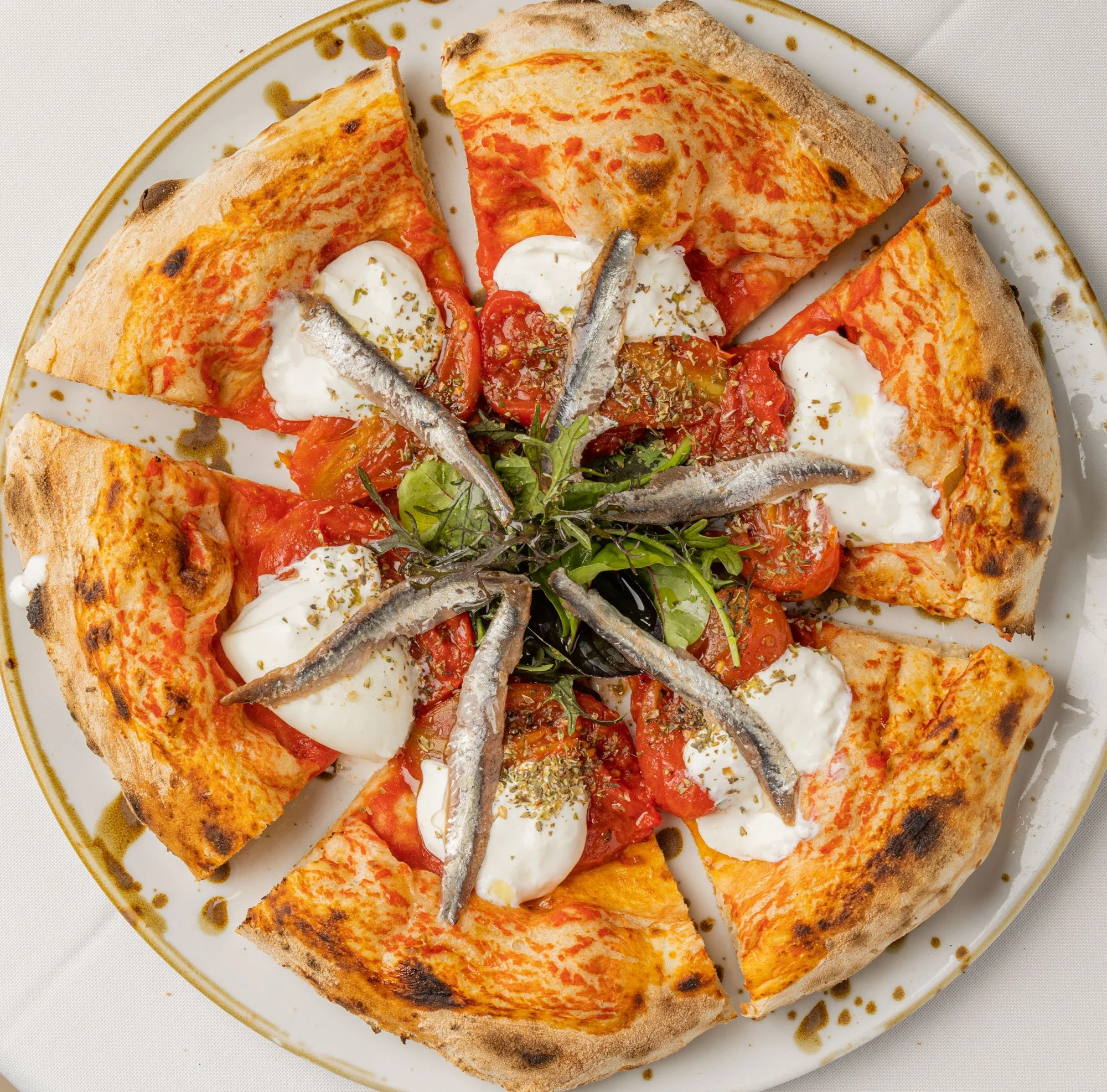 Pizza con pomodoro, mozzarella, acciughe e basilico dense, senza crosta sottile e croccante