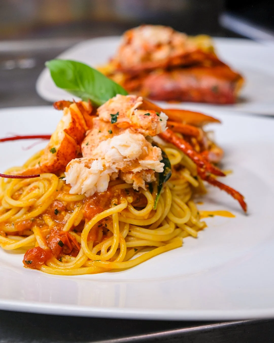 Pasta con frutti di mare, pomodoro e basilico, decorata con un basilico fresco sulla parte superiore.