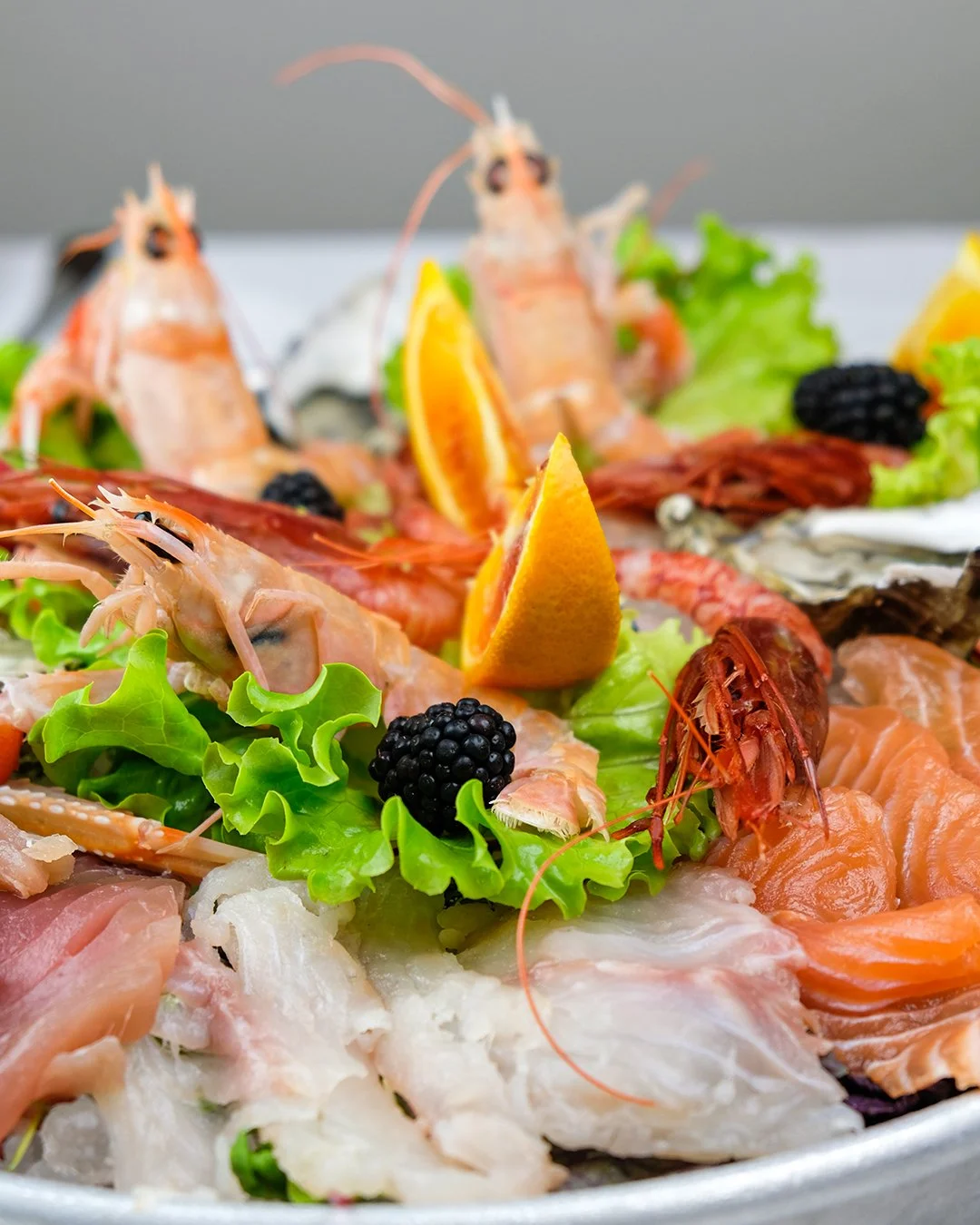 Insalata di frutti di mare con gamberi, salmone, ostriche, limone e more nere