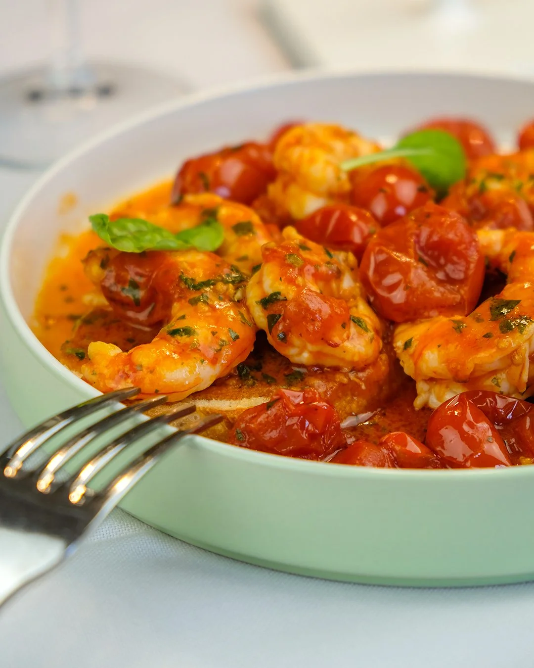 Piatto di gamberetti con salsa di pomodoro e basilico in una zuppiera verde