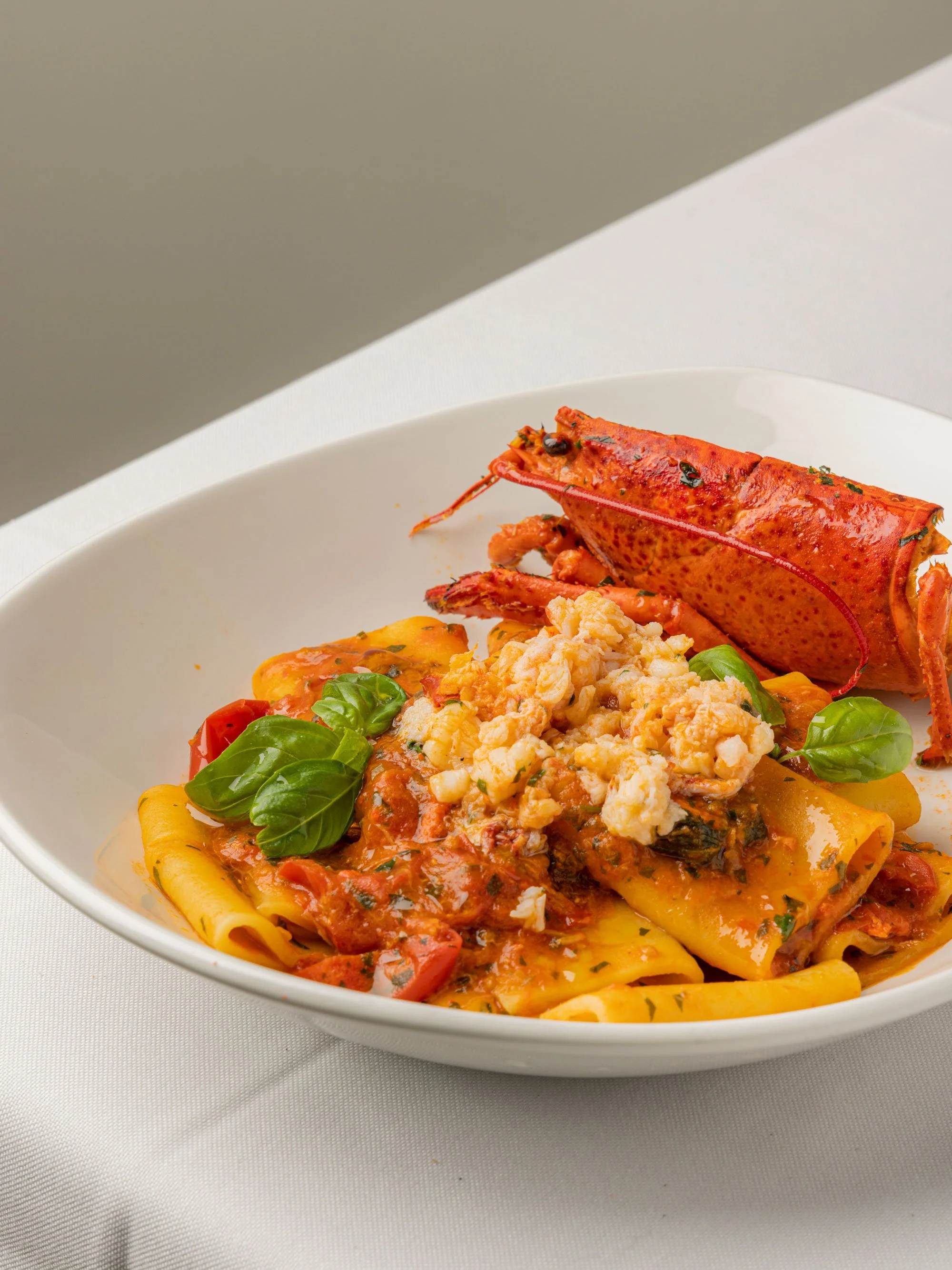 Pasta fresca con salsa di pomodoro, basilico e formaggio, con granchio come decorazione.