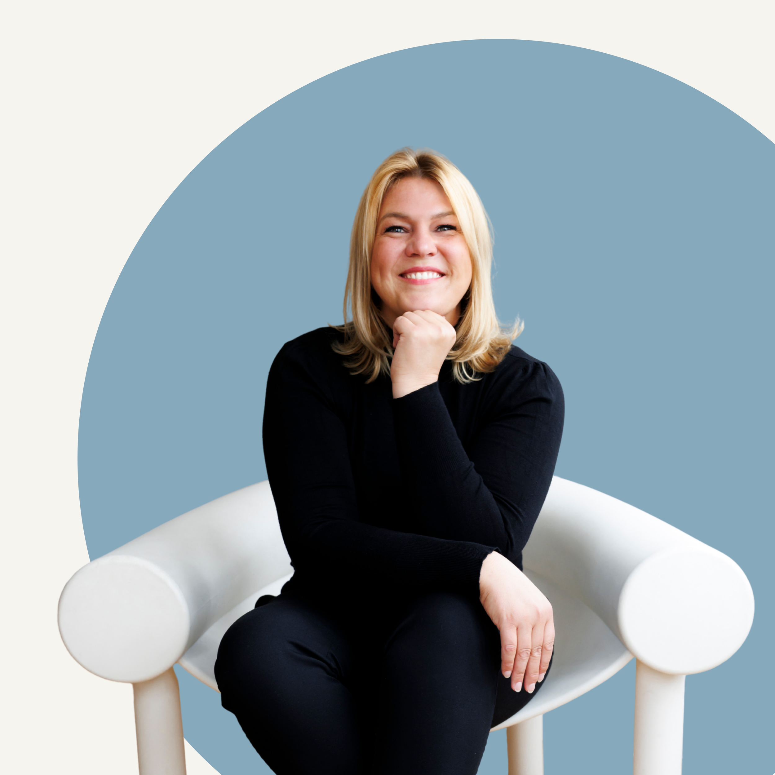Barbara Wucsits sitzt auf weissem Stuhl vor hellblauem Hintergrund.