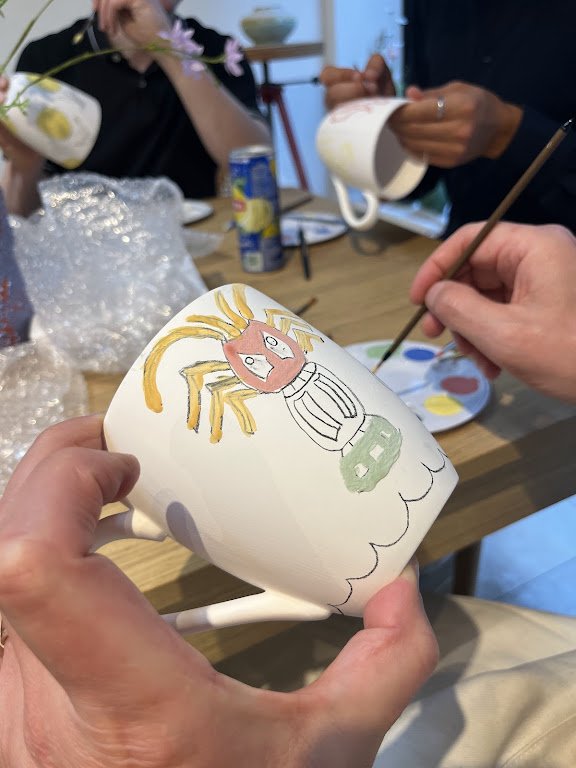 Person die een bloempot beschildert met een tekening van een kreeft.