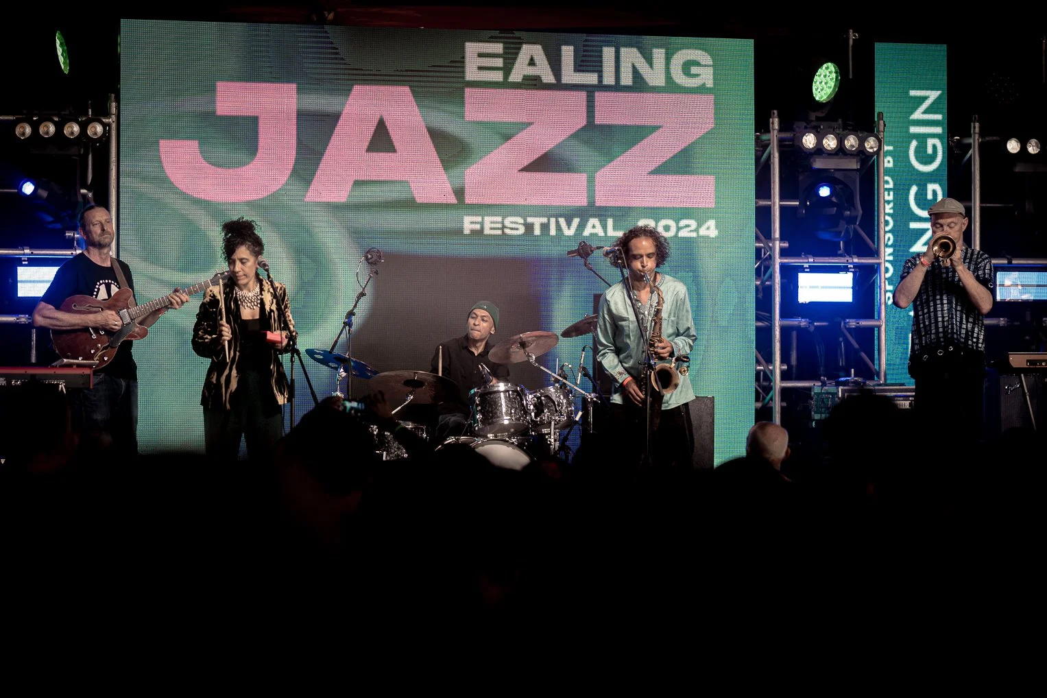 Jazz band performing on stage at the Ealing Jazz Festival 2024 with a large digital screen in the background displaying the event name.