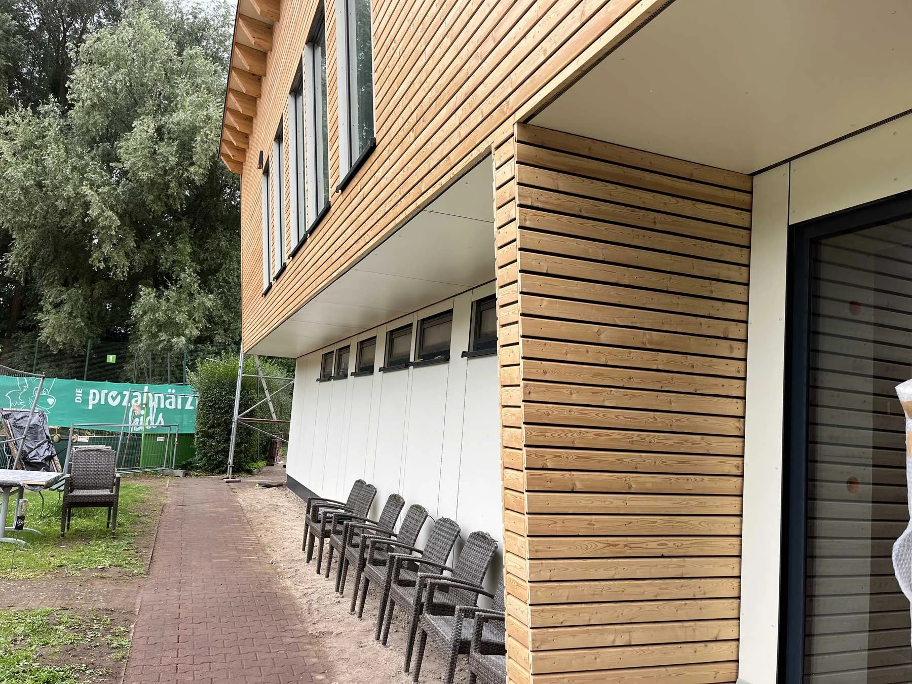 Modernes Vereinsheim des Tennisclubs Schwerin mit Holzfassade, großzügigem Dachüberstand und nachhaltiger Holzbauarchitektur.