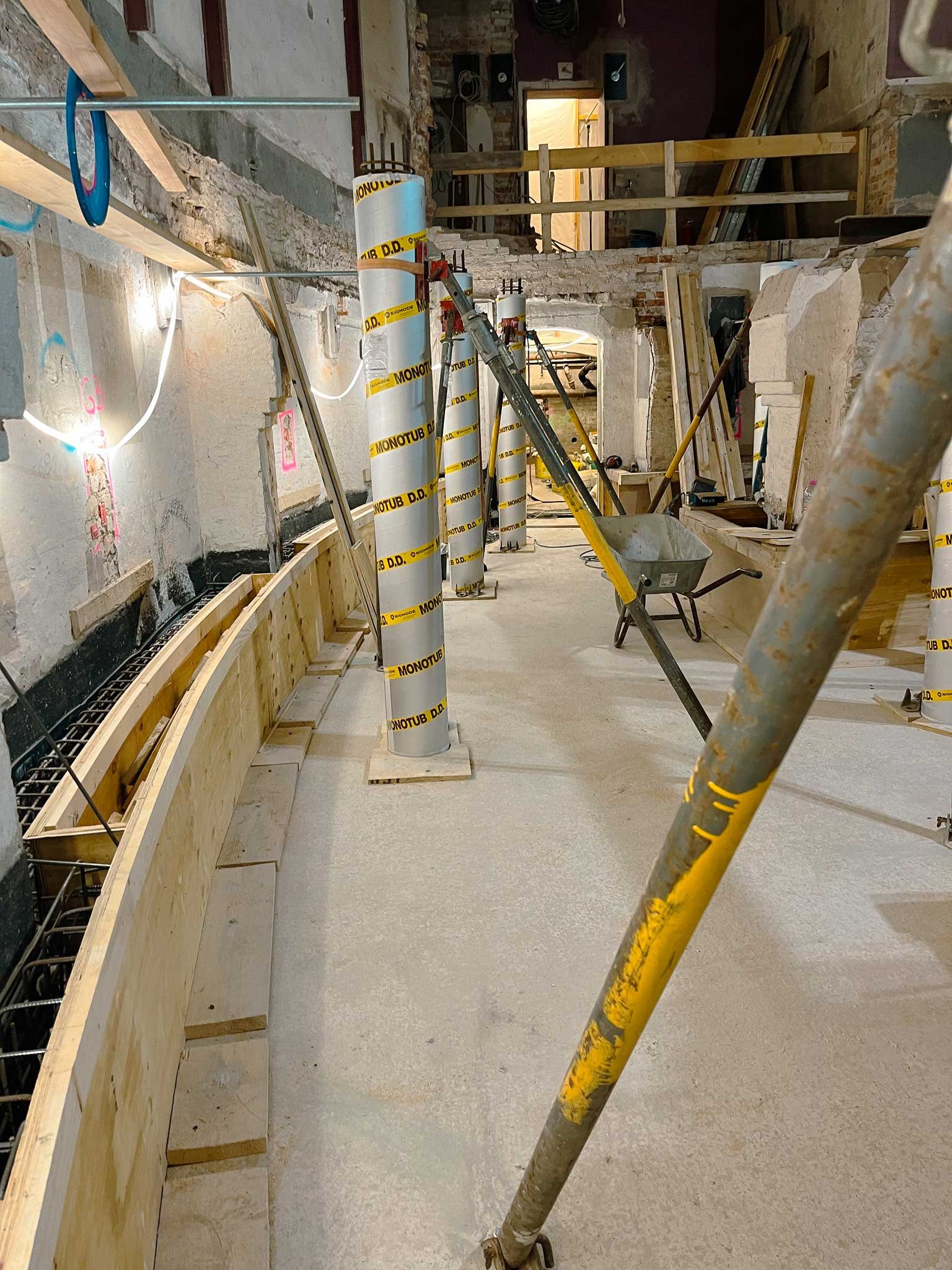 Innenraum einer Baustelle mit Baugerüst, Schutzumwicklung um Rohre, werkzeug und Baumaterialien.