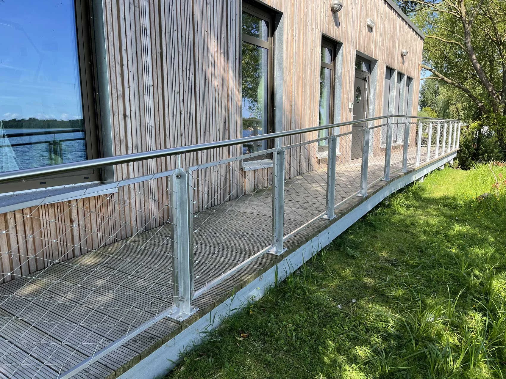 Barrierefreier Zugang mit Rampe an einem modernen Gebäude der Wasserschutzpolizei mit Holzfassade in Uferlage.