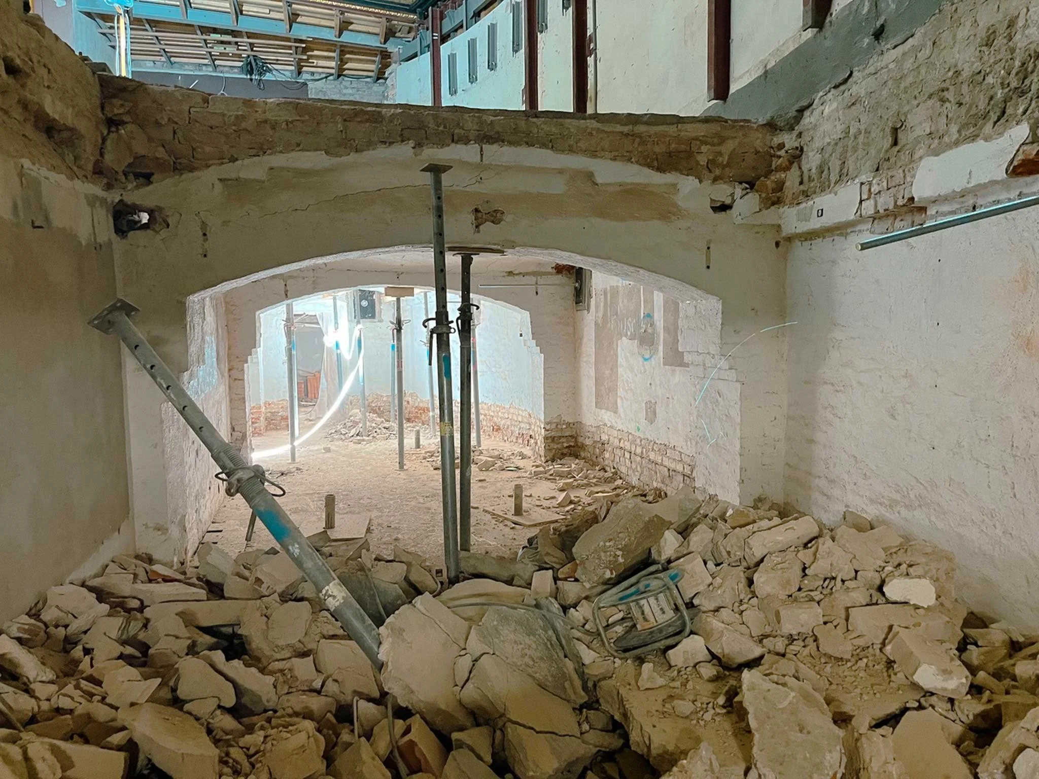 Innenansicht einer Baustelle mit abgerissenen Mauern, Konstruktionsstützen und herumliegenden Steinen.