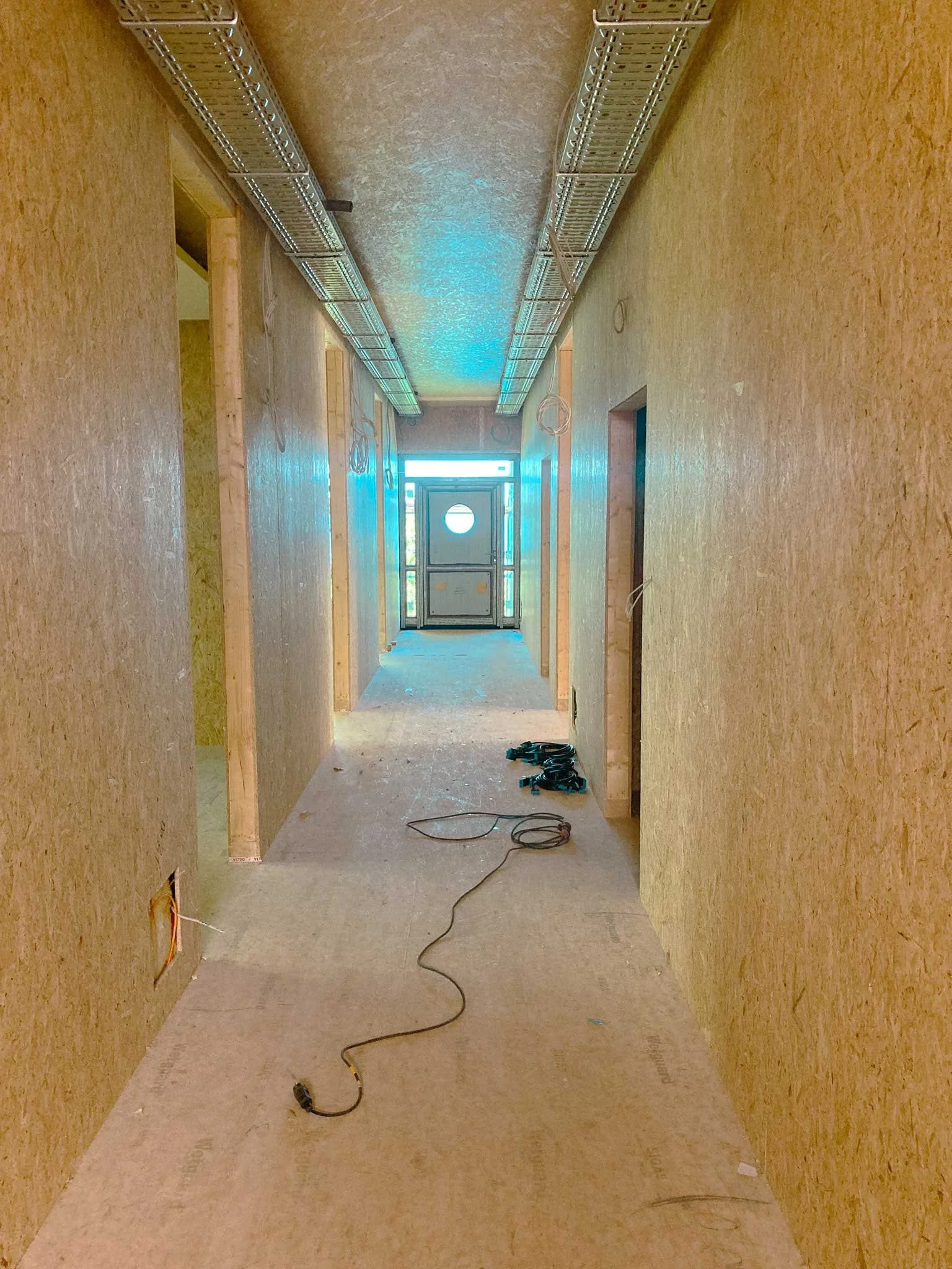 Innenansicht eines unter Konstruktion stehenden Flurs mit offener Decke und Kabeln auf dem Boden.