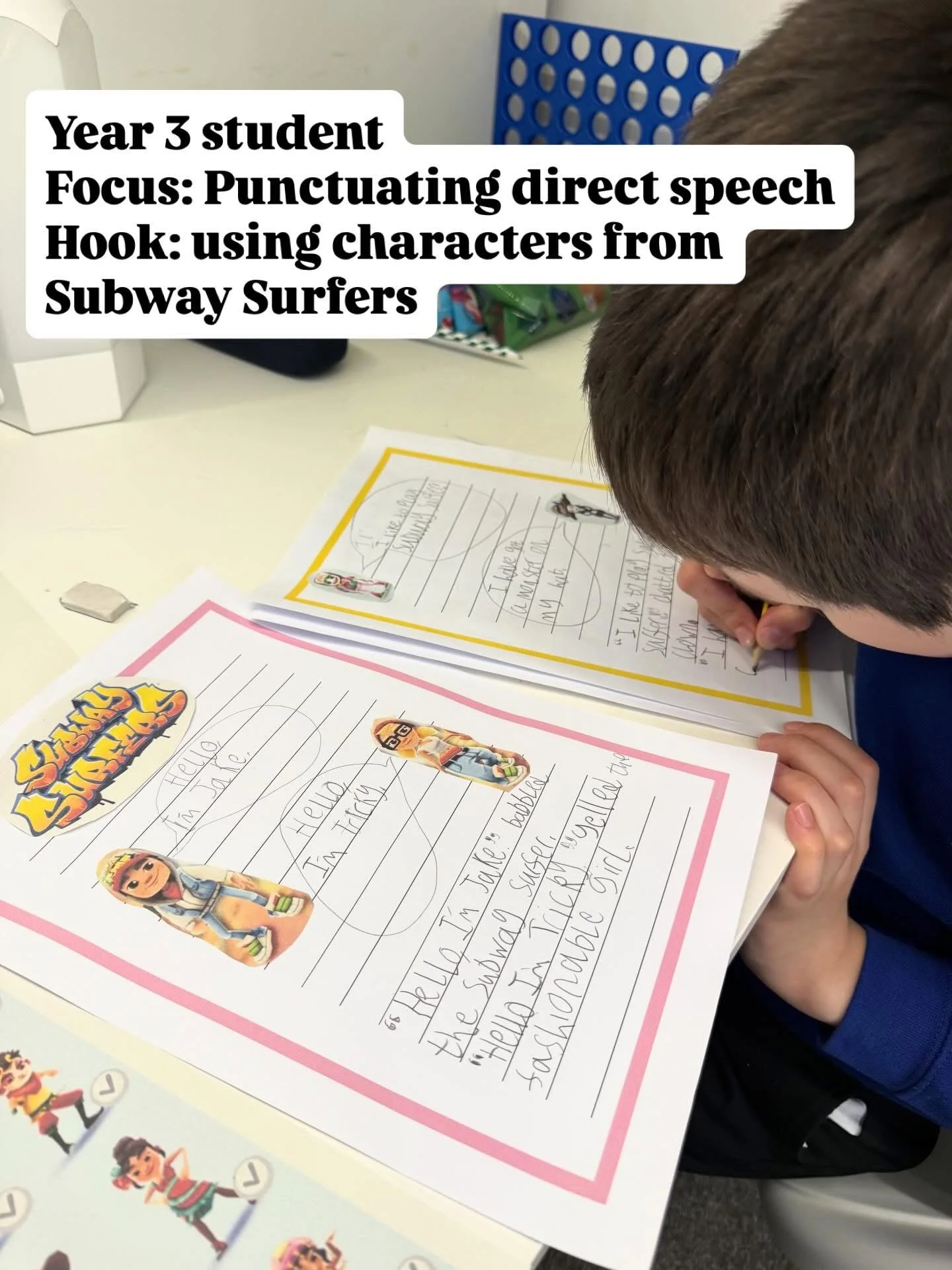 A young boy is writing on a piece of paper with a crayon, focusing on his writing. The paper has colorful borders and stickers of characters from Subway Surfers. The surface in front has additional stickers of animated characters and a small eraser.